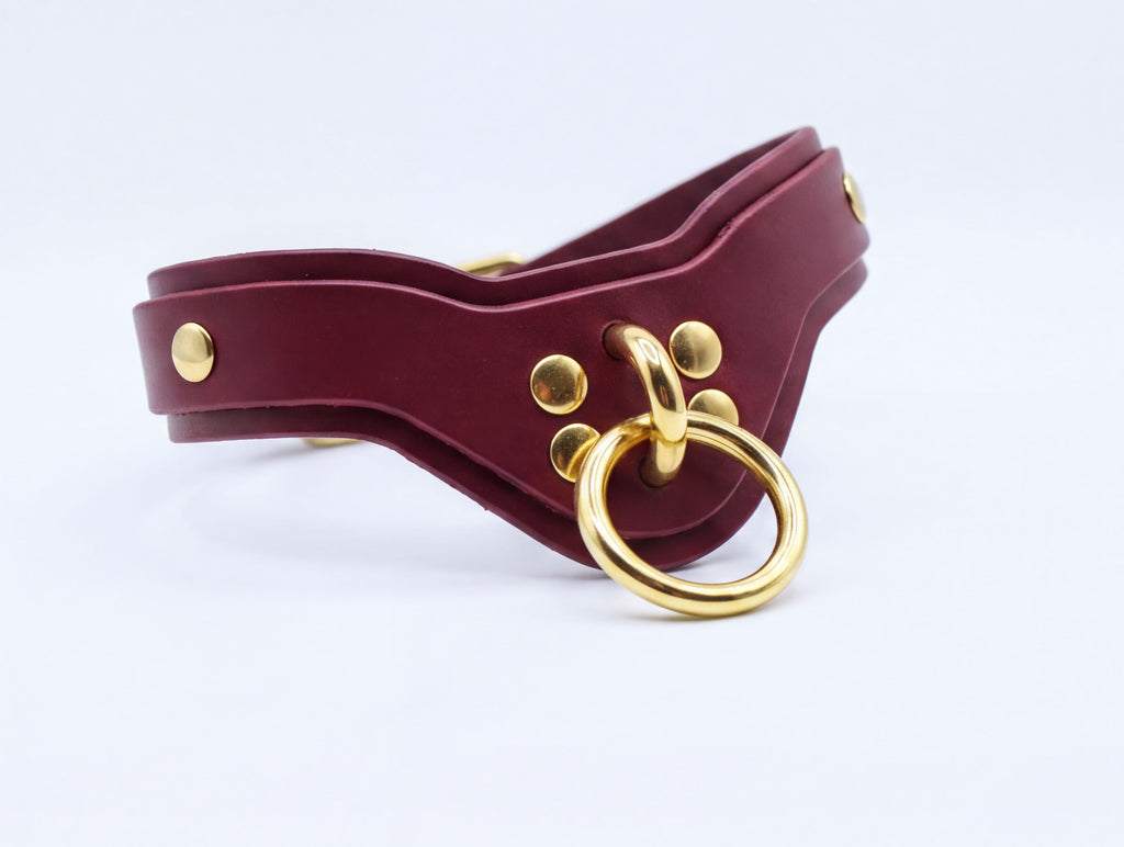 A burgundy leather choker necklace with a gold-colored metal ring and a gold-colored metal buckle.