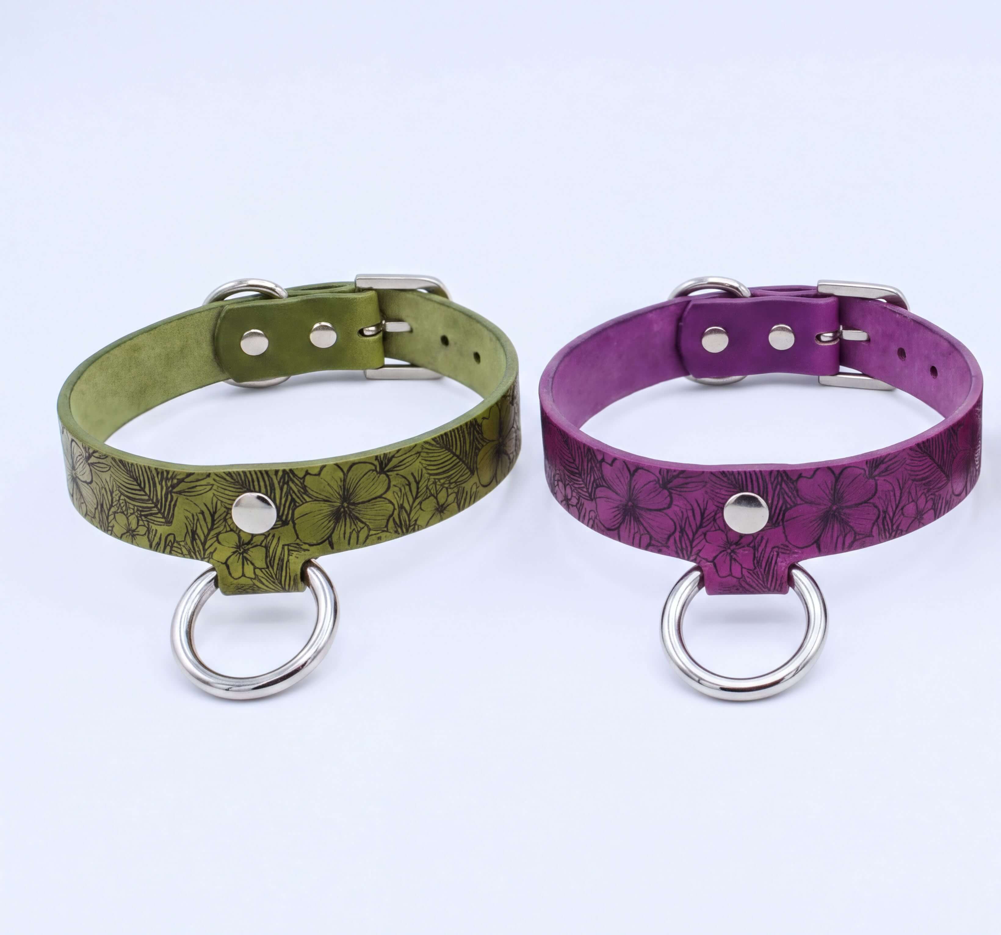 two leather choker necklaces with metal rings and buckles, one in green and the other in purple.