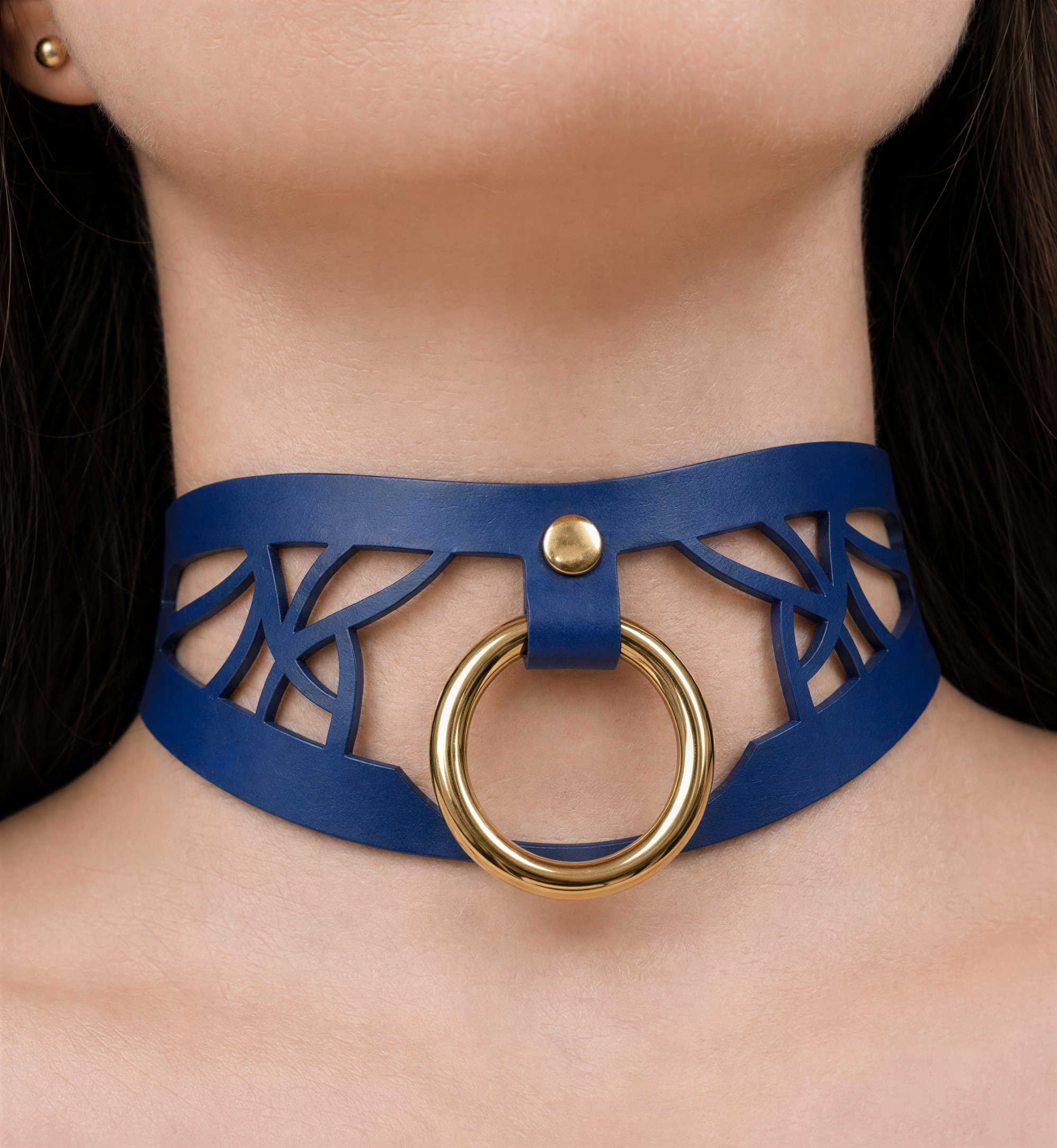 A close-up of a woman's neck wearing a blue choker necklace with a gold ring.