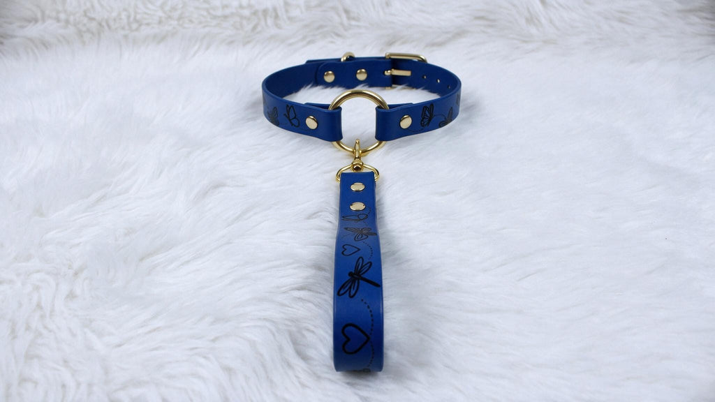 A blue collar with a gold buckle and handle is displayed on a white furry surface.