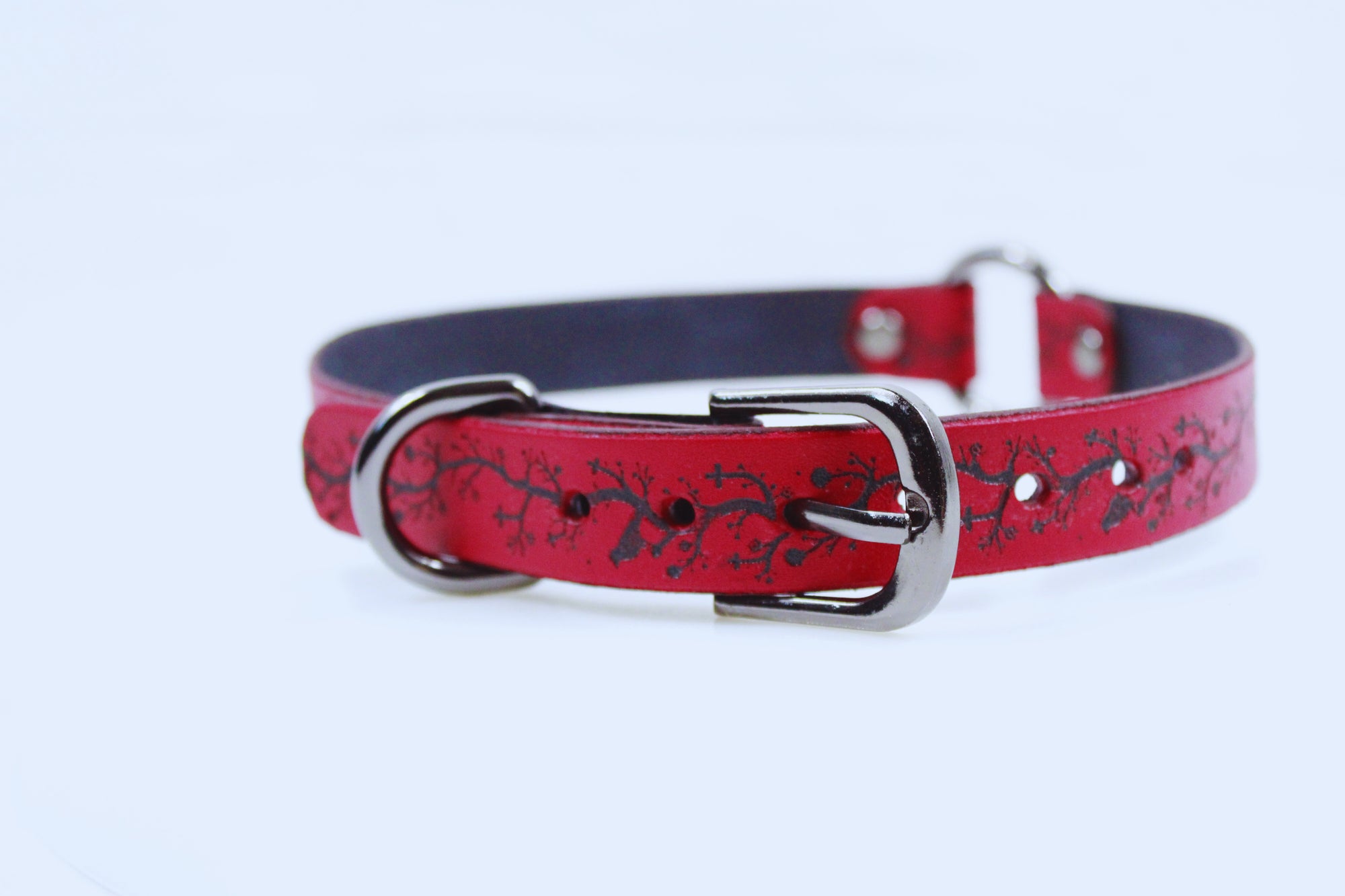 A red leather dog collar with a black tree branch design on it.