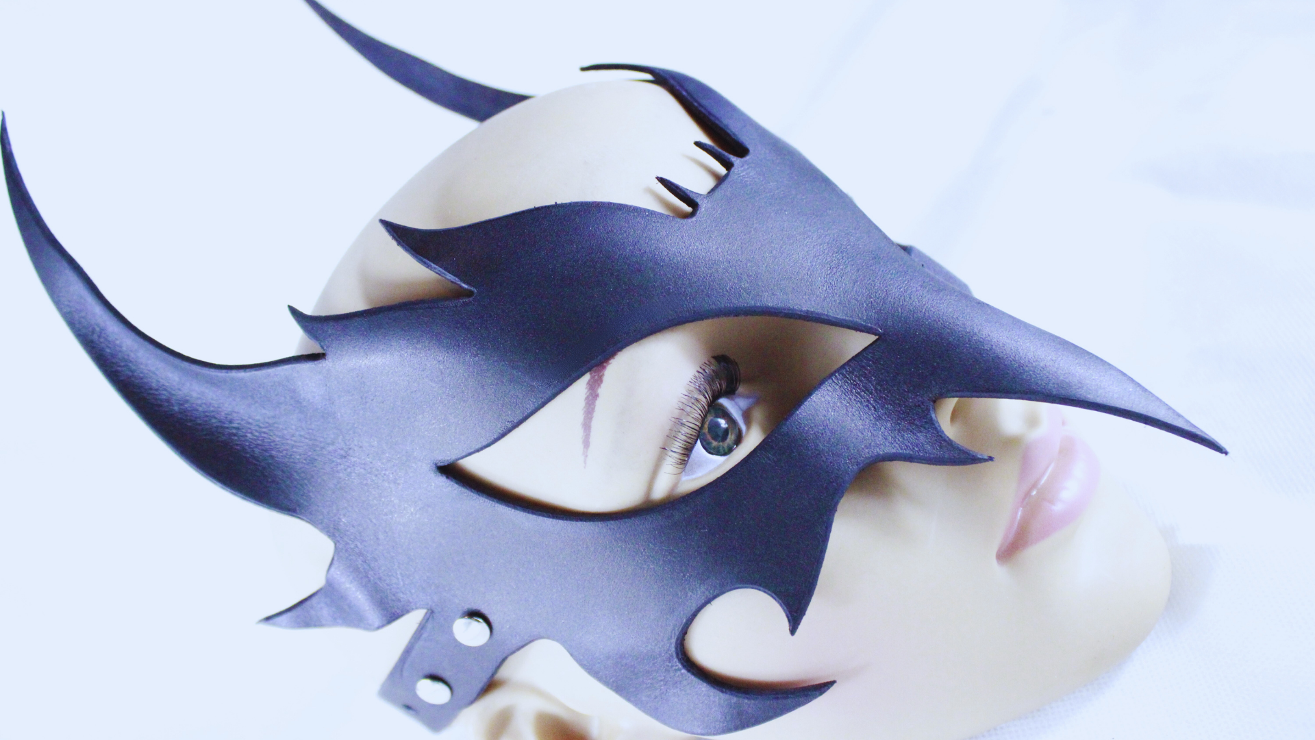 A close-up of a dark blue mask with sharp, pointed edges and a pointed nose, covering a person's face.