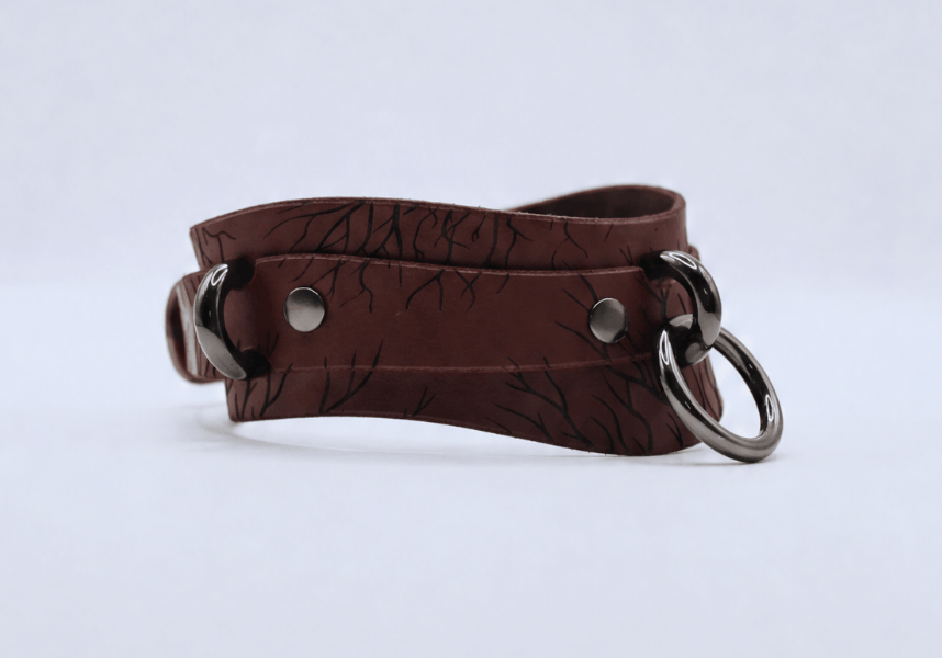 A brown leather choker necklace with metal rings and a metal clasp.