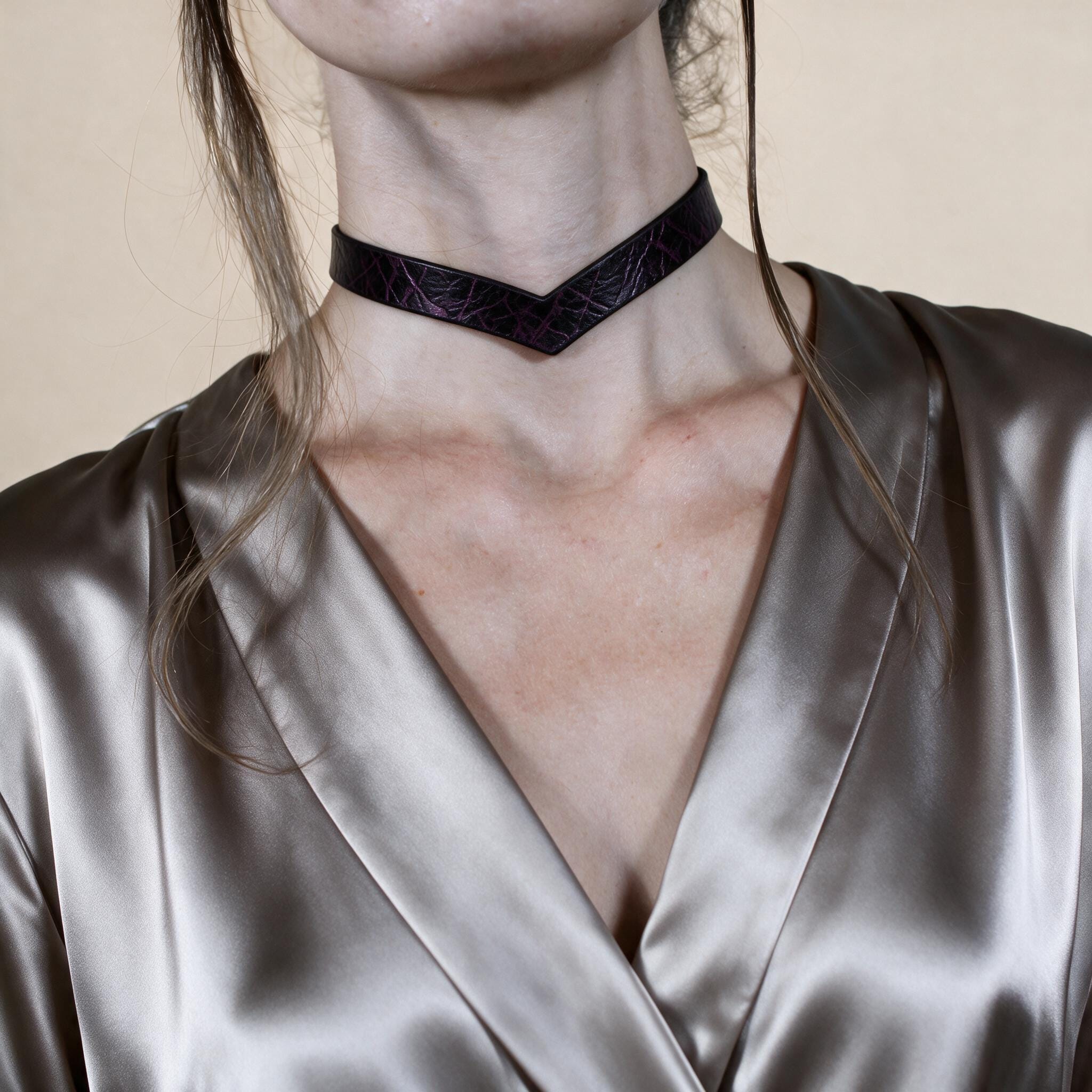 A close-up of a woman wearing a choker necklace with a dark purple pattern.