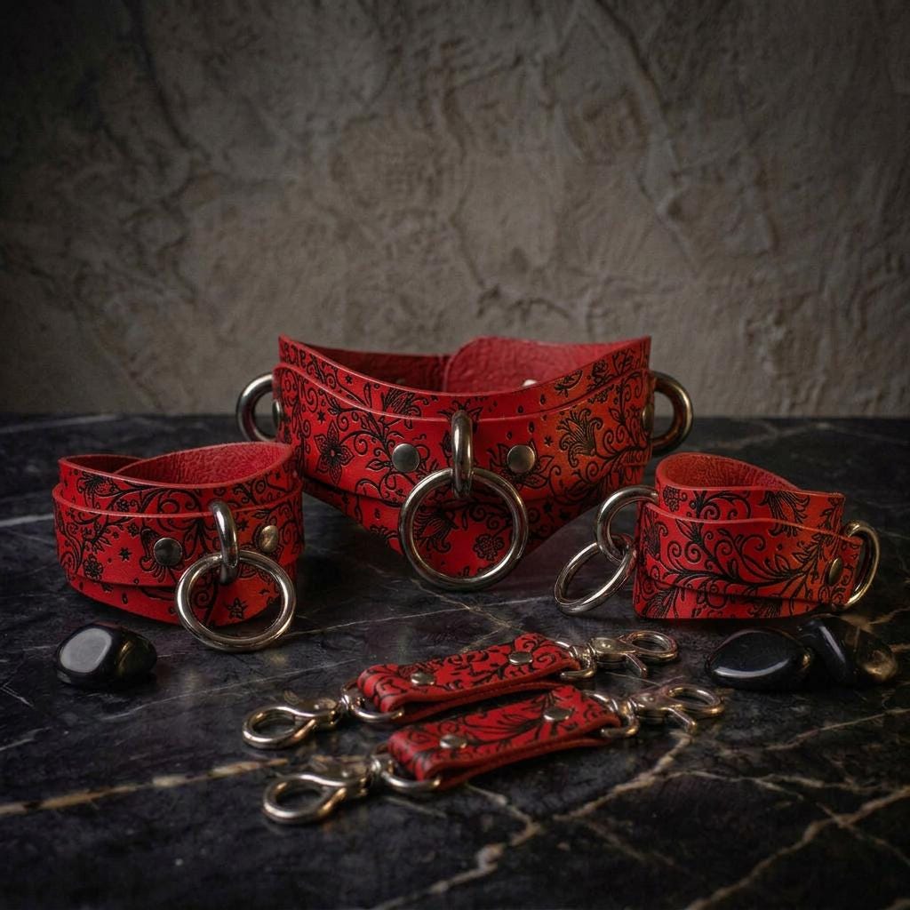 a collection of red leather straps with metal rings and buckles, arranged on a dark surface.