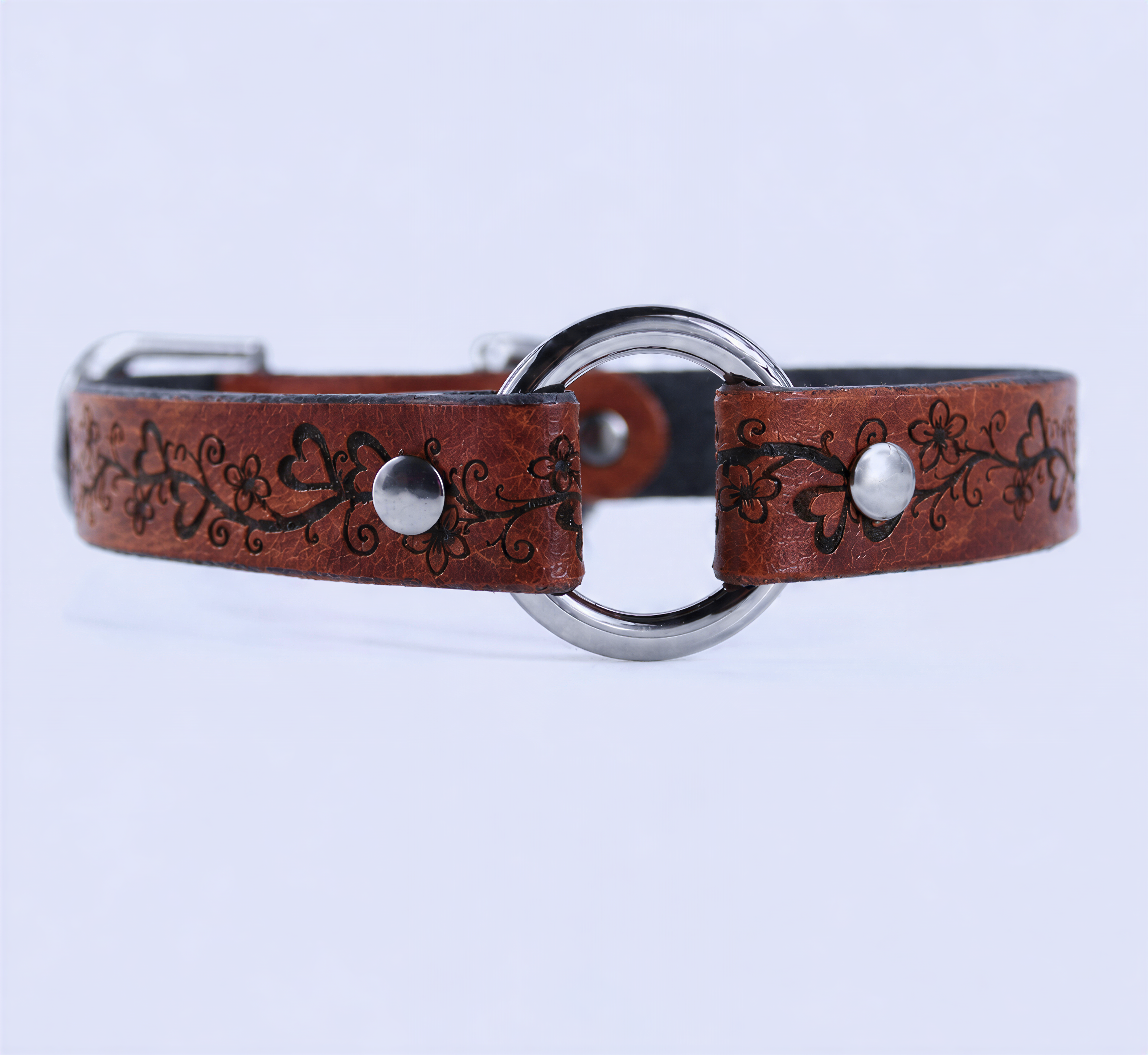 A brown leather collar with a metal ring and floral designs.