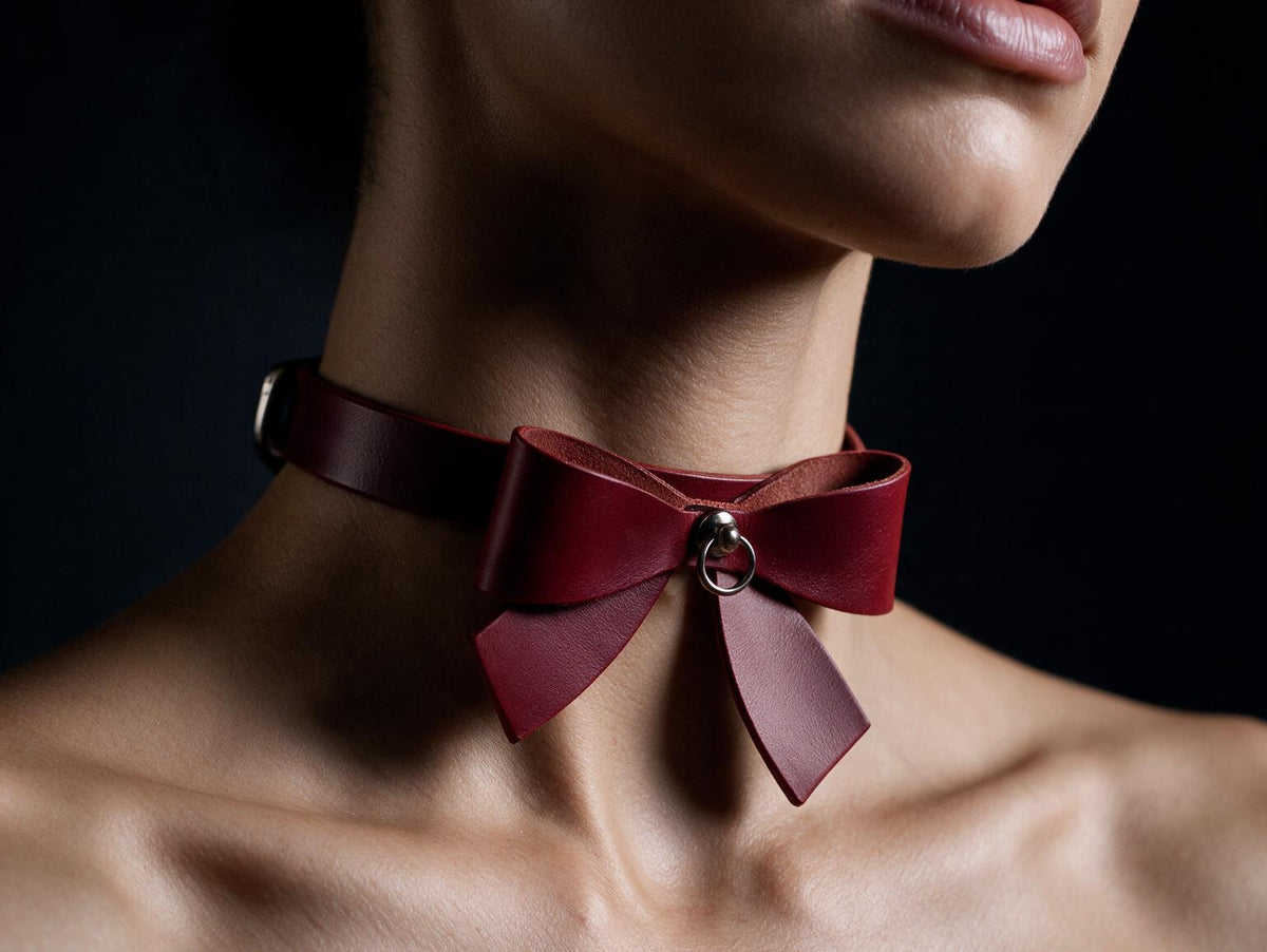 A close-up of a person's neck wearing a red leather choker with a bow detail.