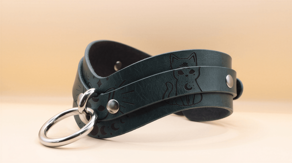 A dark green leather choker necklace with a cat design and metal rings.