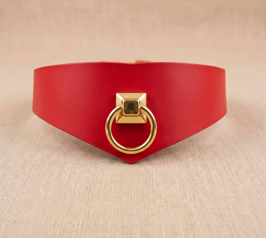 A red leather choker necklace with a gold-colored metal ring on the front.