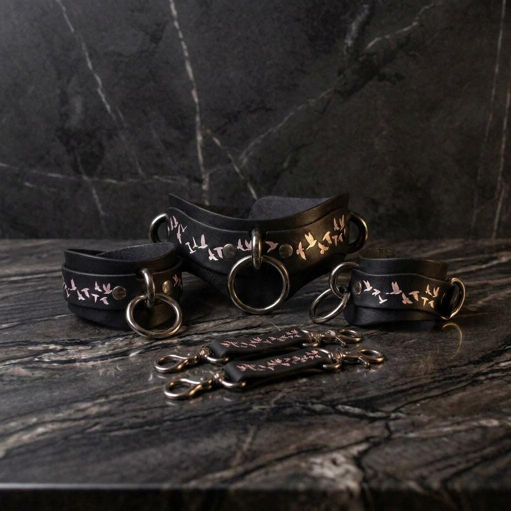 a set of black leather straps with metal rings and handles, arranged on a marble surface.