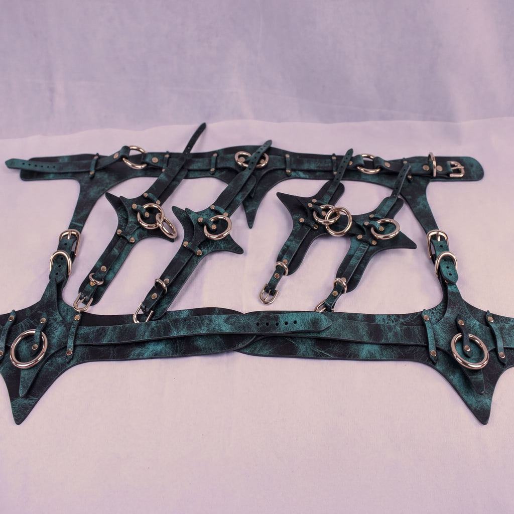 A collection of dark green leather straps with metal studs and buckles, arranged in a grid-like pattern.