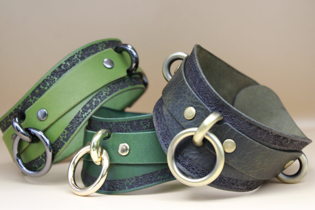 three leather choker necklaces with metal rings and buckles, arranged in a row.