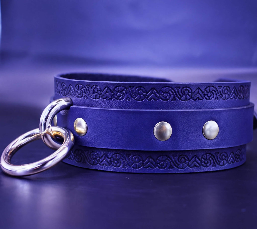 A blue leather choker necklace with metal rings and decorative elements.