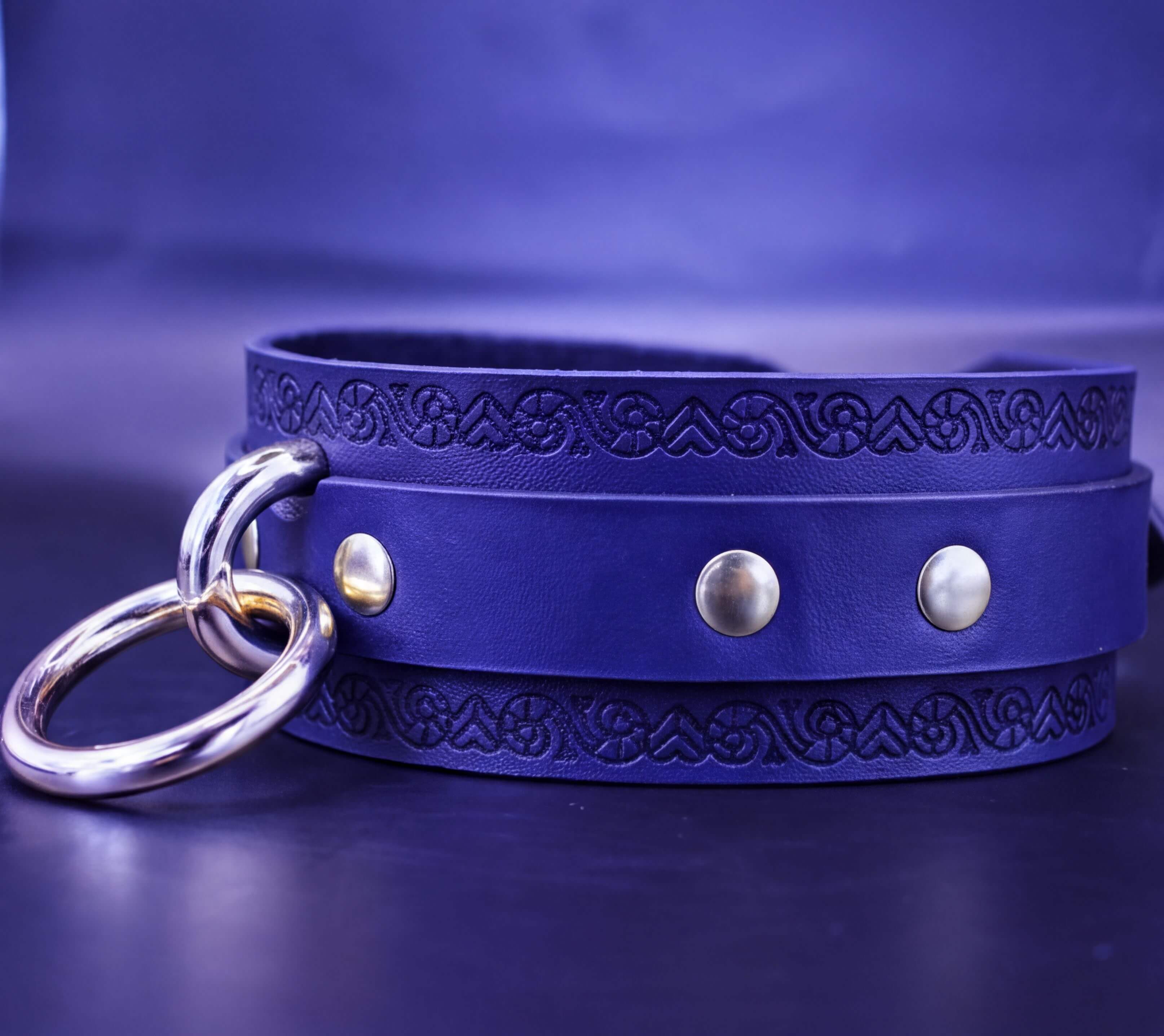 A blue leather choker necklace with metal rings and decorative elements.