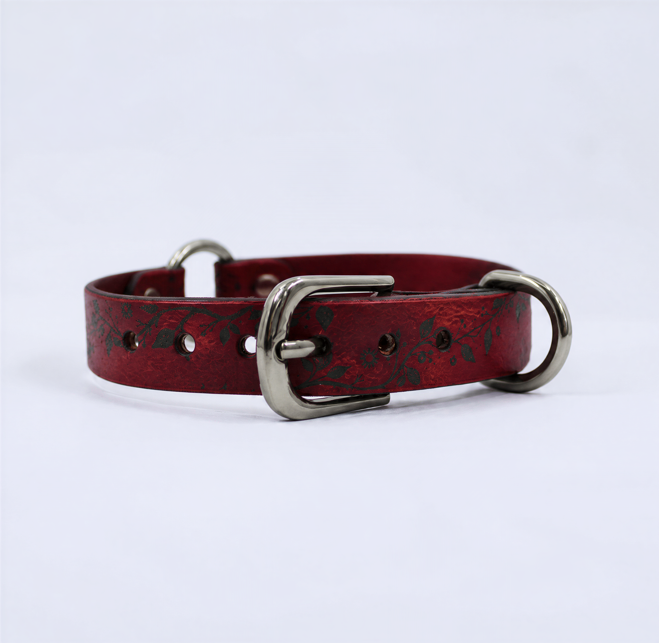 A red leather dog collar with metal buckles and a floral pattern.