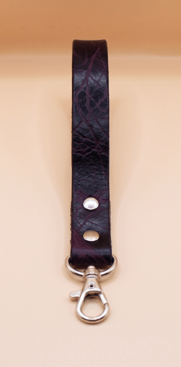 A dark purple leather strap with a silver metal clasp and hook attached to it.