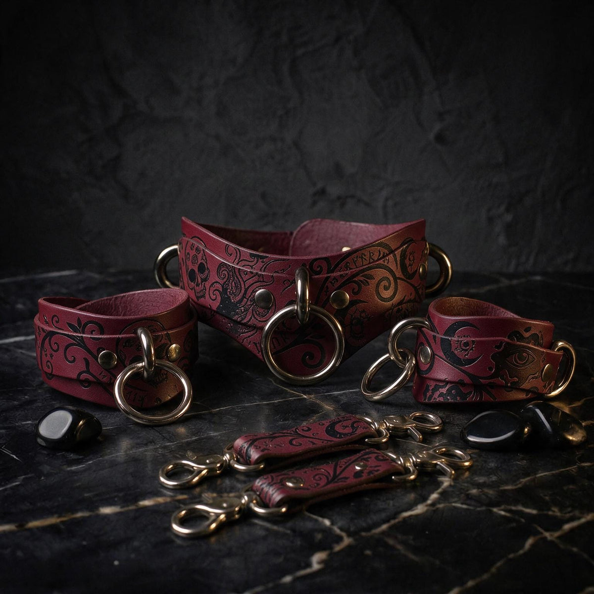 A collection of burgundy leather straps with intricate black designs, arranged on a dark surface.