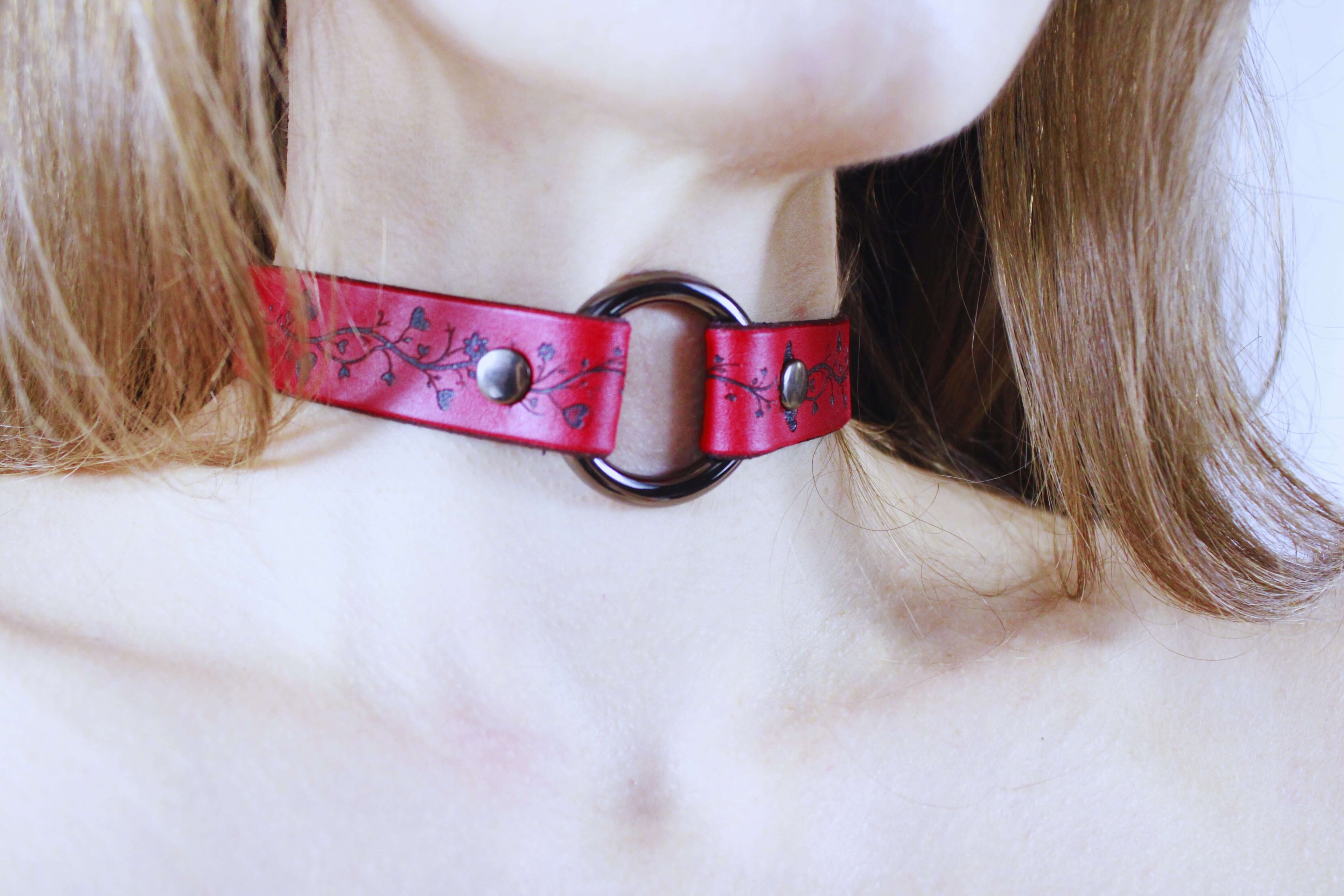 Vine Pattern Submissive Collar in red leather, featuring vine motifs and a central metal ring.