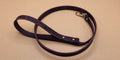 A purple leash with a silver buckle is shown on a beige surface.