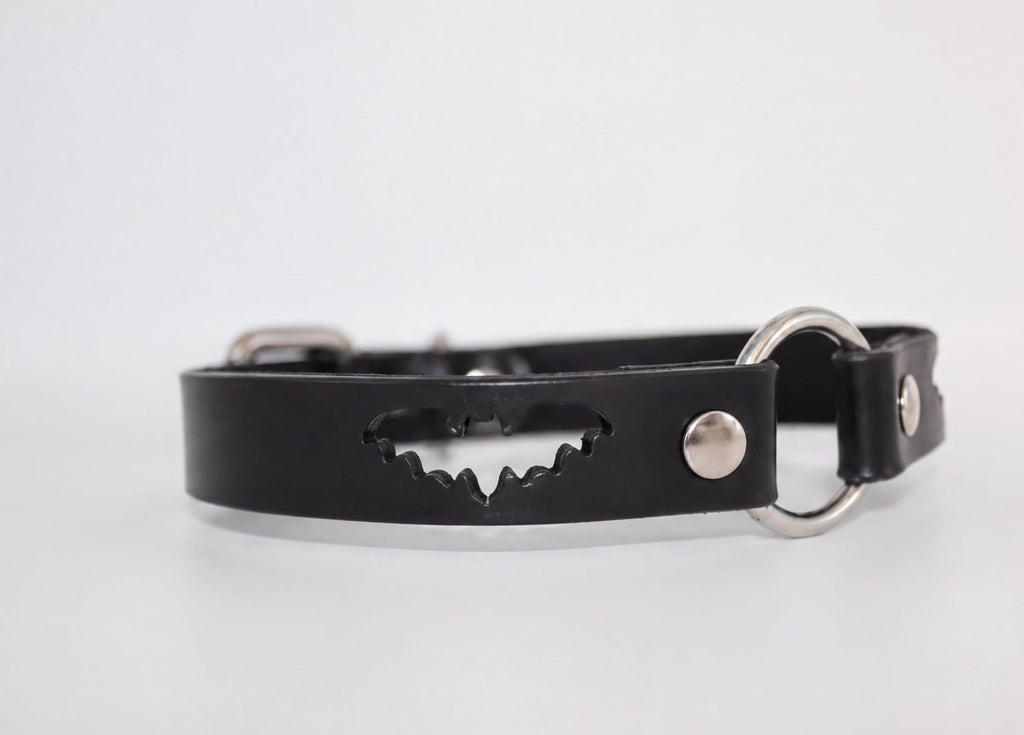 A black leather collar with a bat-shaped cutout in the center.