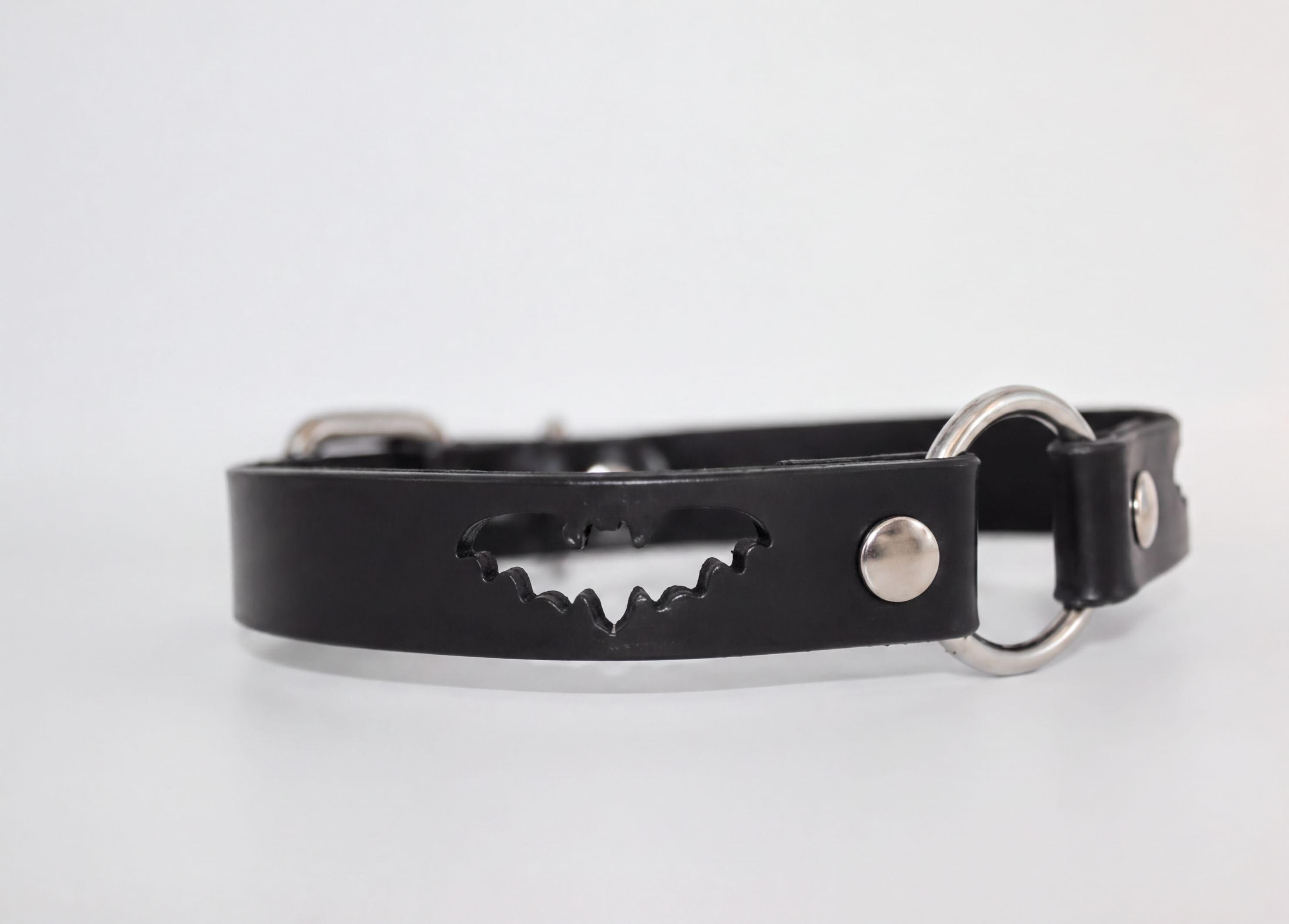 A black leather collar with a bat-shaped cutout in the center.