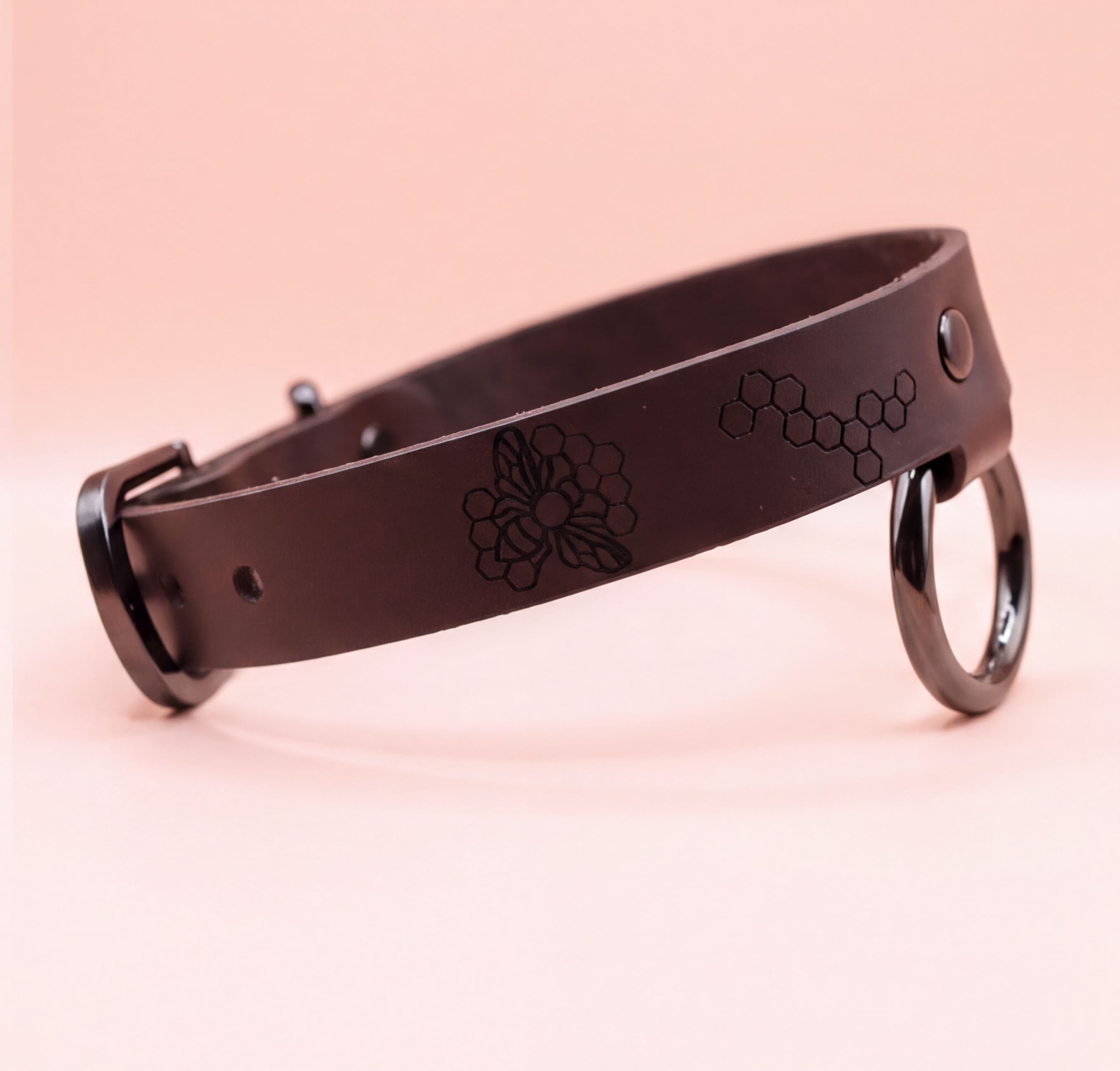 A black leather collar with a metal buckle and a floral design on the strap.