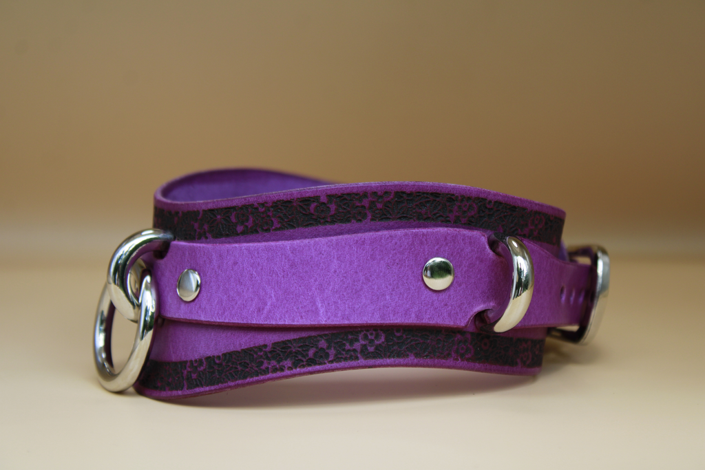 A purple leather choker belt with silver metal rings and buckles.