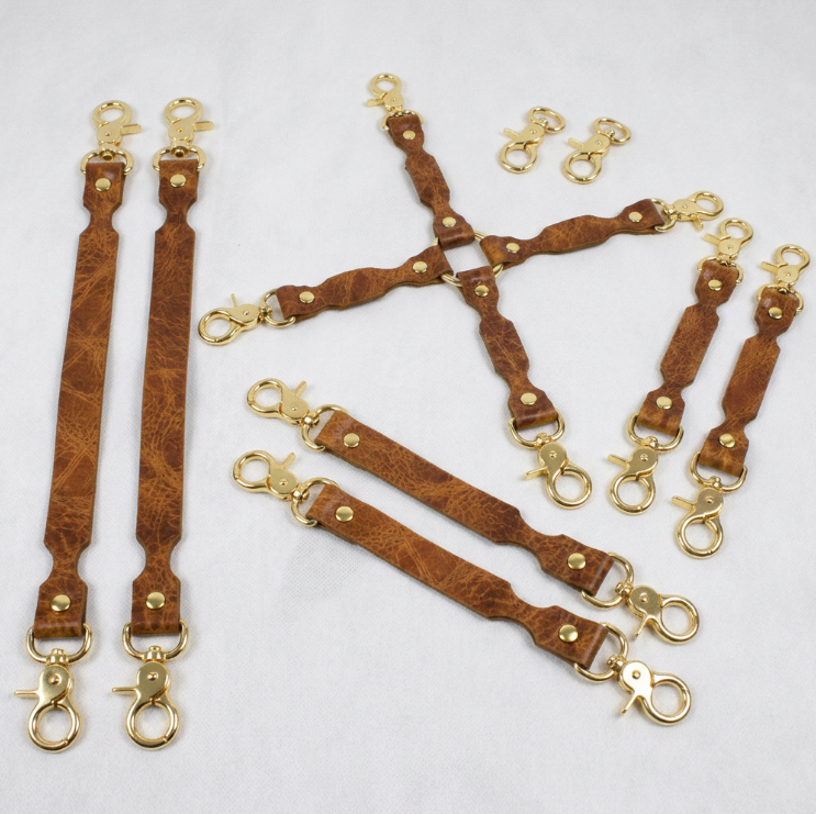 a collection of brown leather straps with gold metal clasps, arranged on a white background.