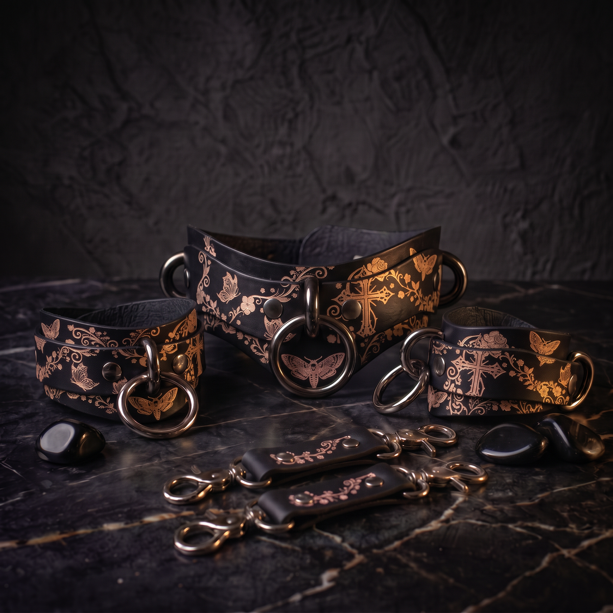 a collection of ornate leather straps and buckles, featuring intricate floral and butterfly designs, arranged on a dark surface.