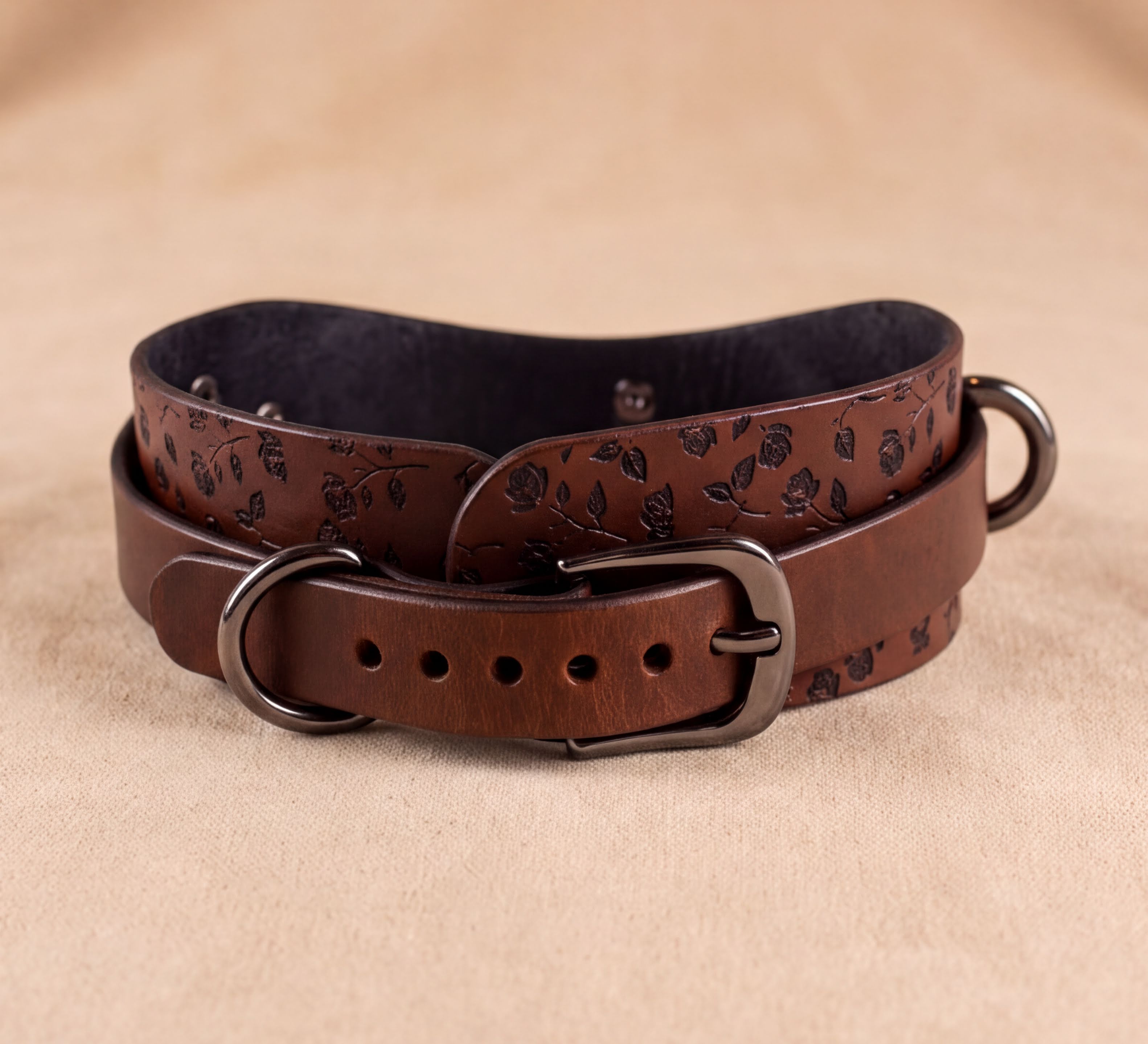 A brown leather belt with a floral pattern, featuring a buckle and a buckle hole.