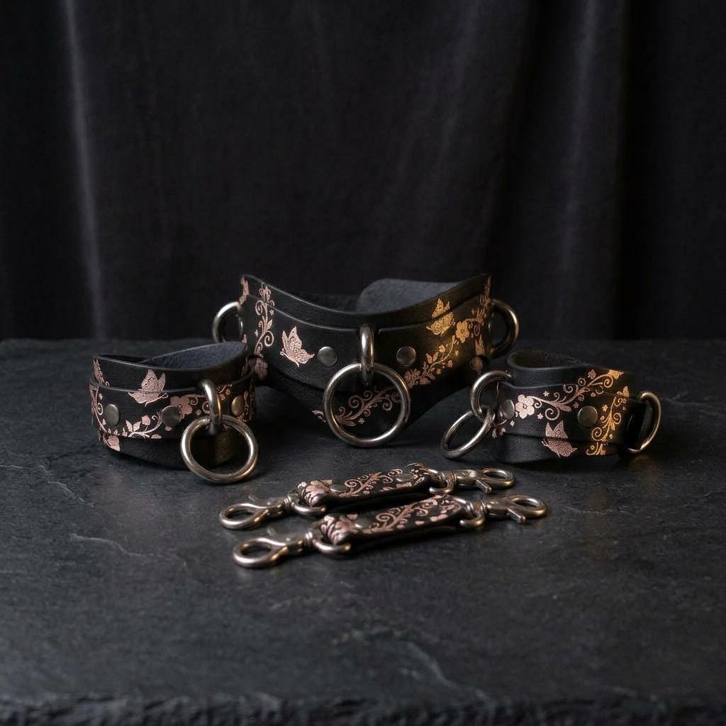 a collection of ornate leather straps and buckles, featuring intricate floral and leaf designs, arranged on a dark surface.
