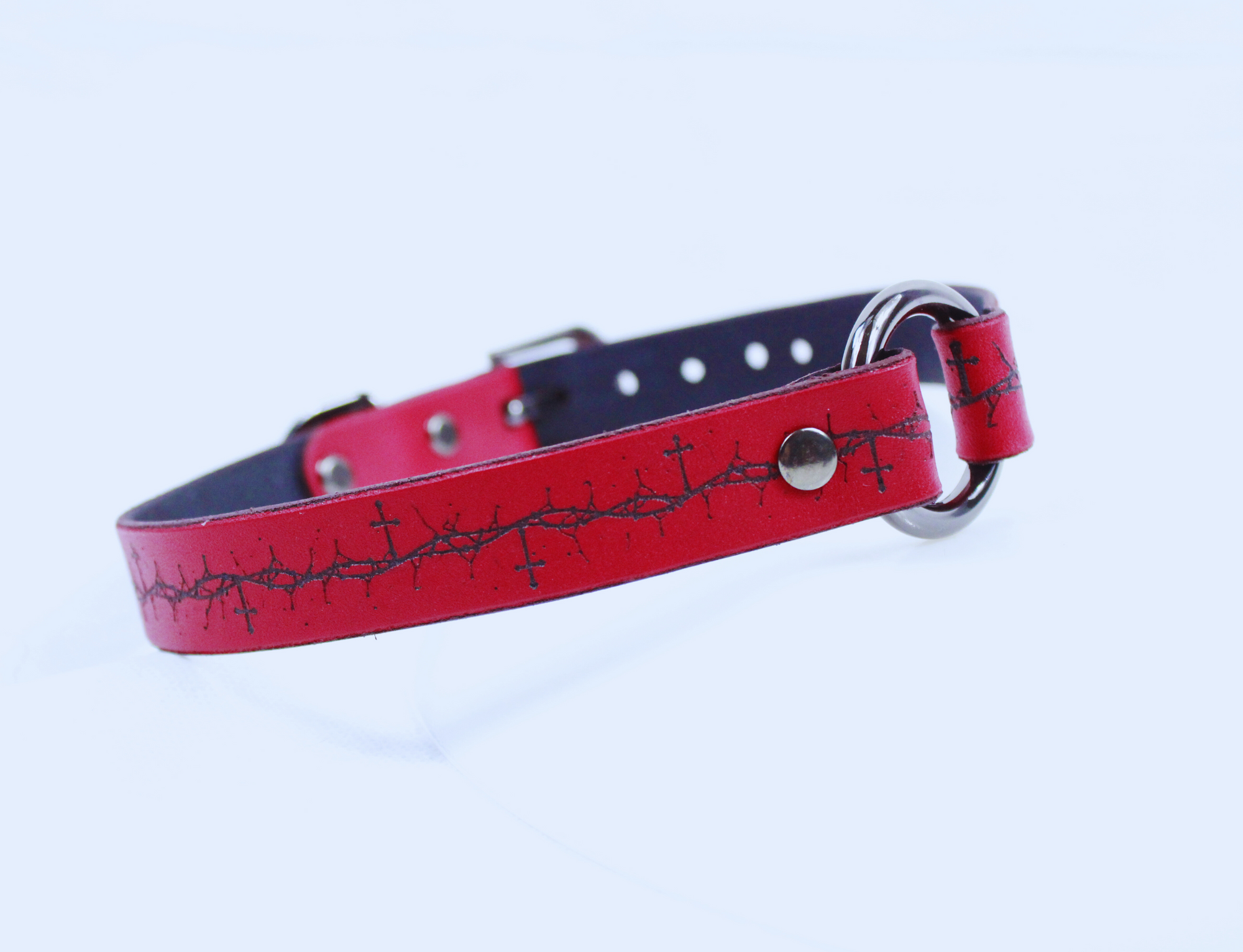 A red leather dog collar with a black cross pattern on it.