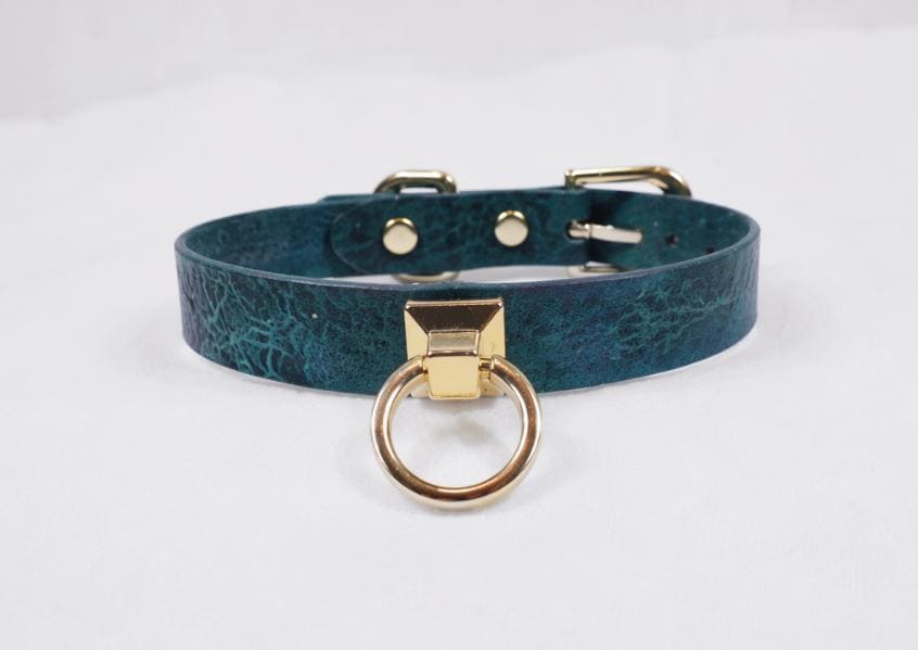 A teal-colored leather choker collar with a gold-colored metal ring and buckle.