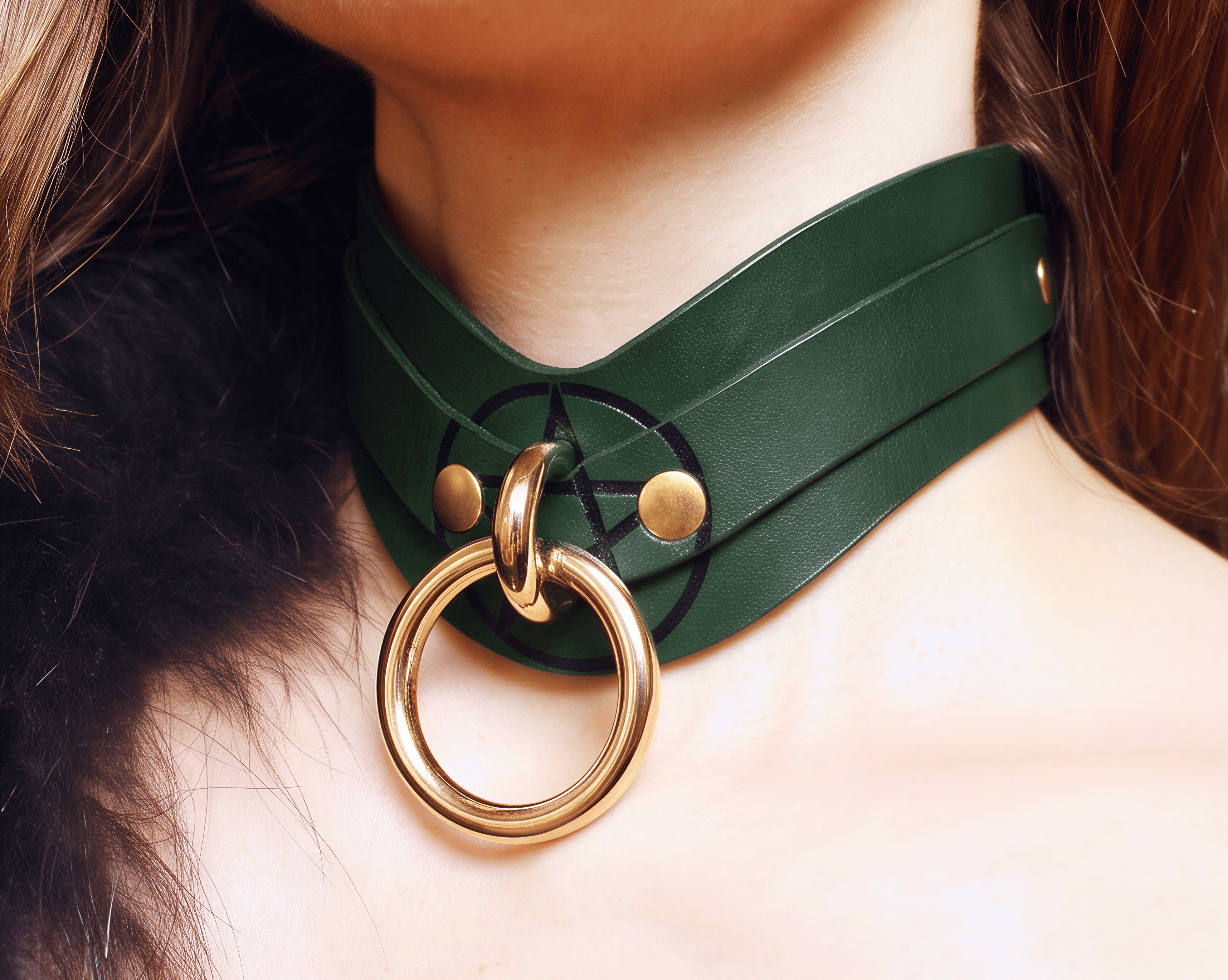 A close-up of a person's neck wearing a green leather choker necklace with a gold ring.