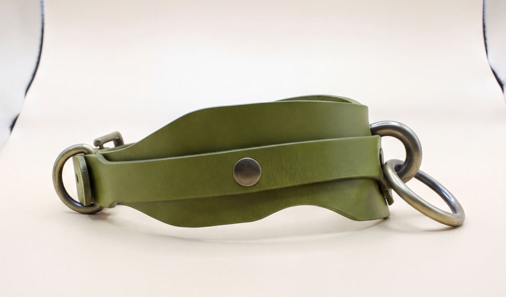 A green leather strap with metal rings and a metal buckle is shown in the image.