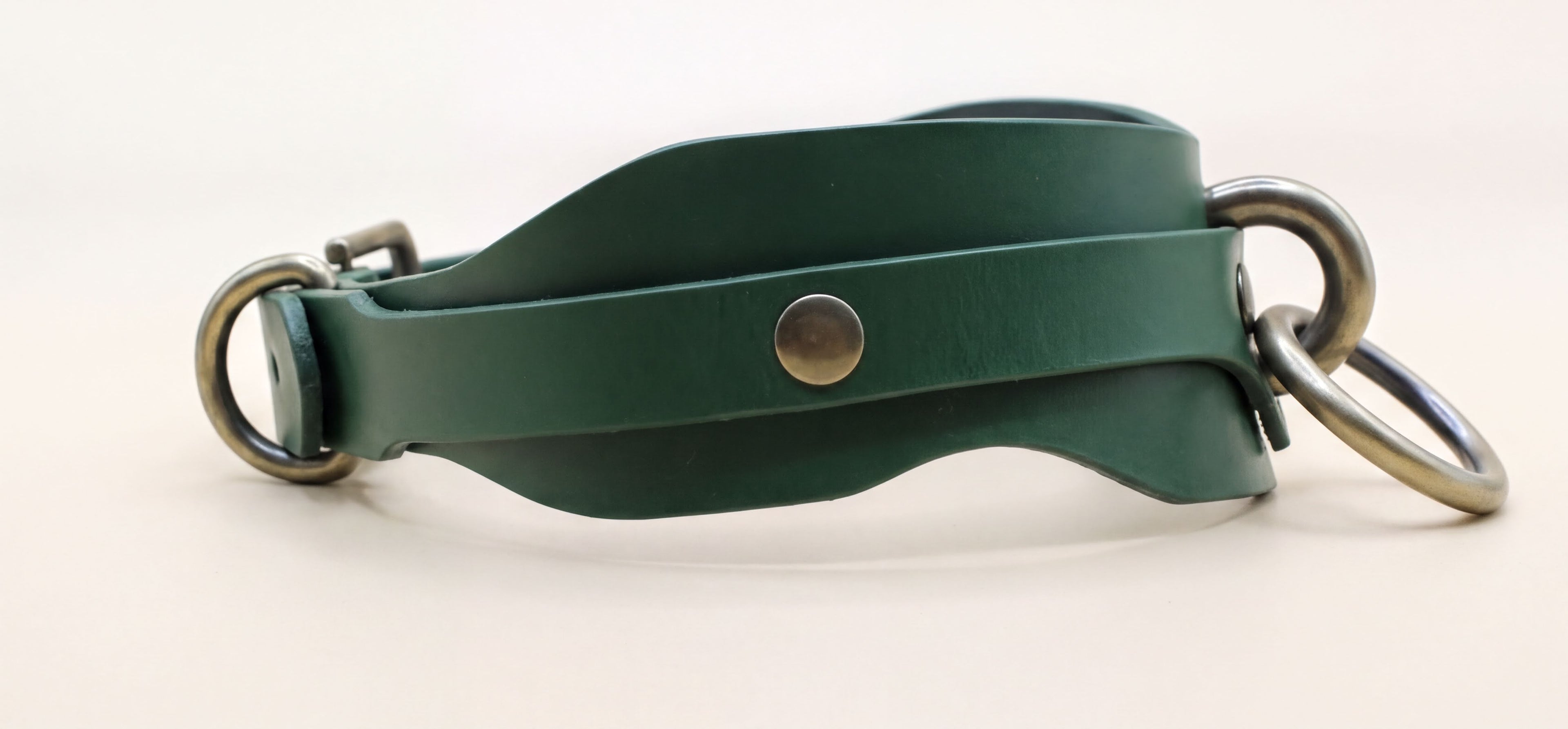 A green leather strap with metal rings and a button is shown in the image.