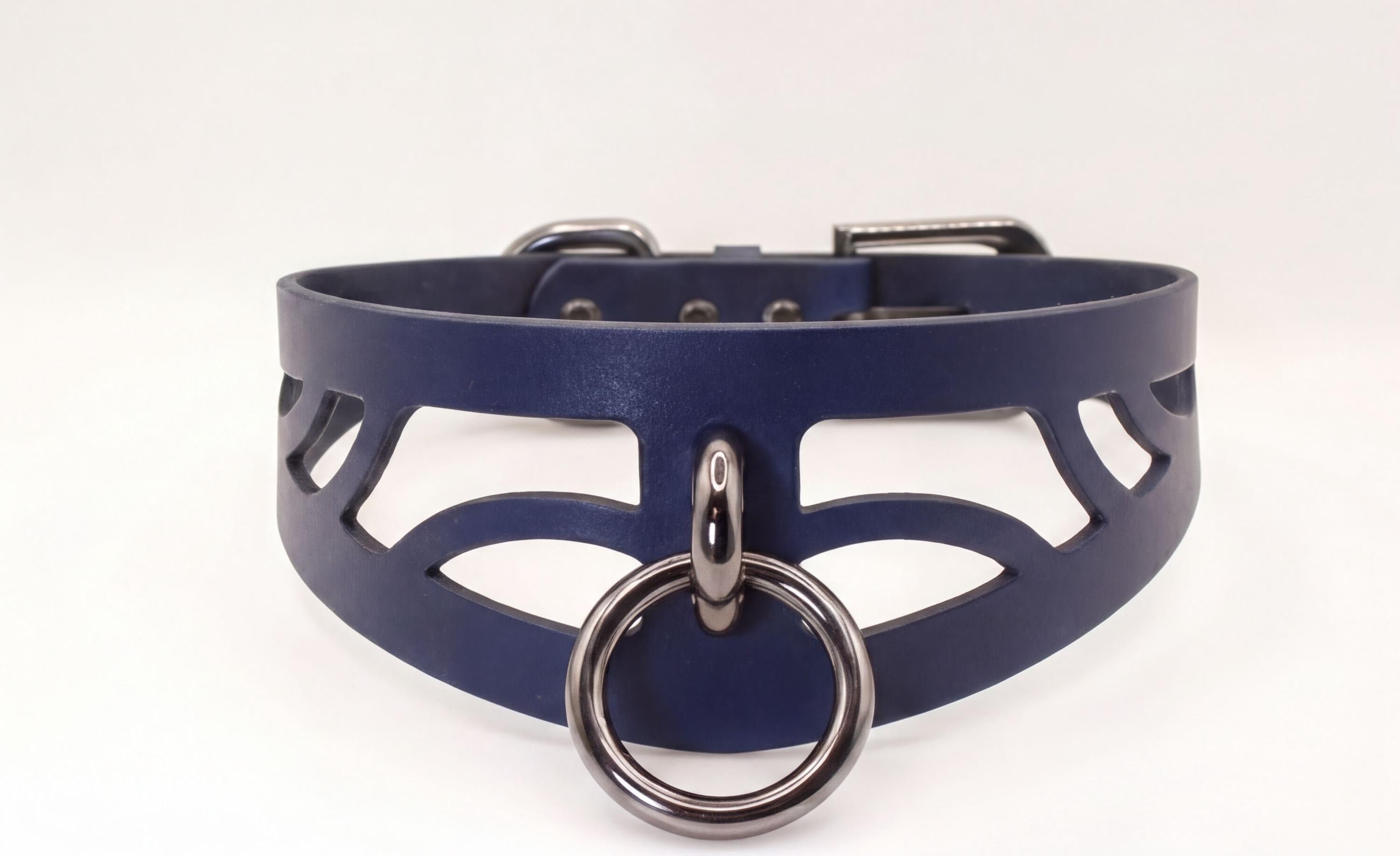 A close-up view of a dark blue choker necklace with a metal ring and a cutout design on the front.