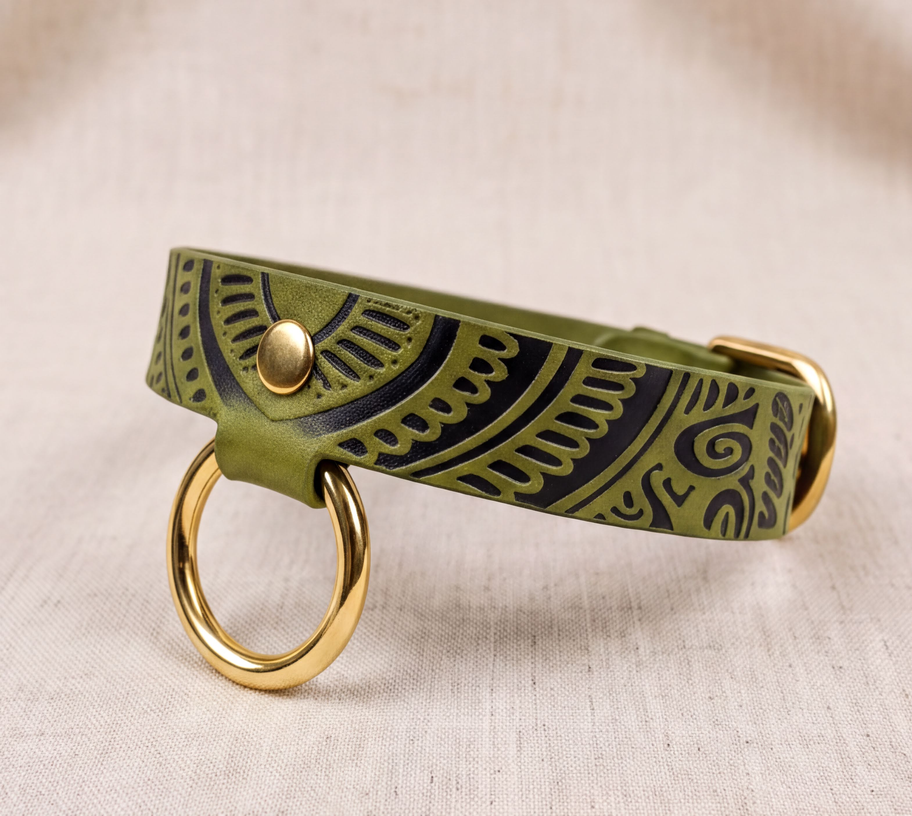 A green leather dog collar with a gold-colored metal ring and a decorative pattern on the collar.
