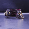 A dark purple leather choker necklace with gold-colored metal rings and a decorative pattern on the clasp.