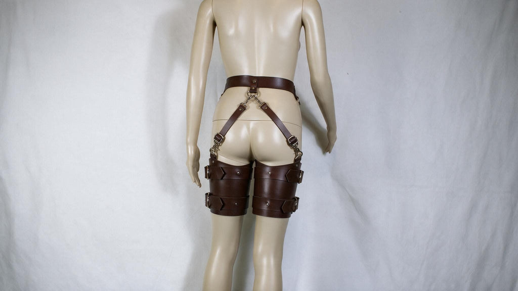 A mannequin wearing a pair of brown leather garter belts and garter straps.