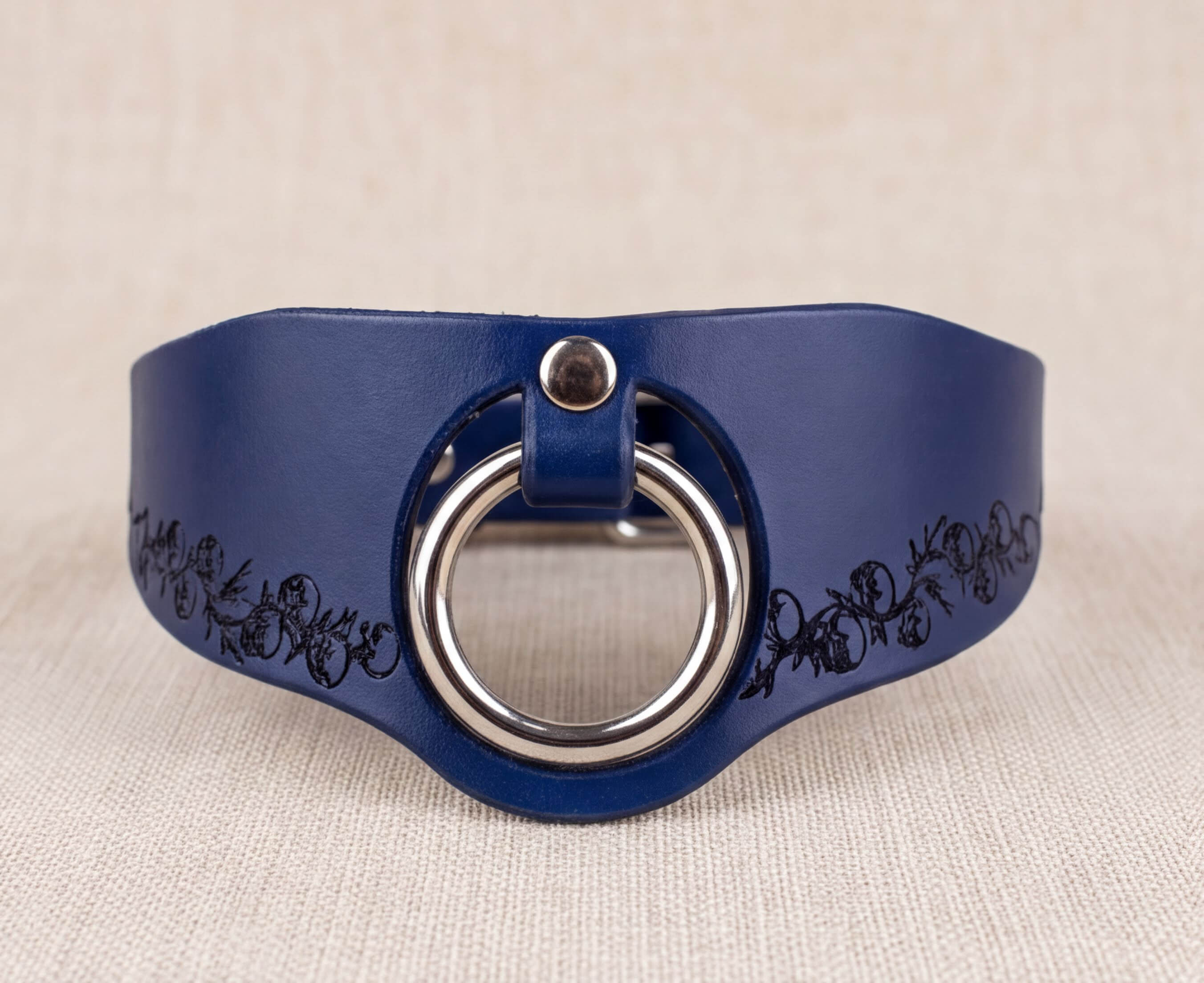 A blue leather choker necklace with a silver ring and floral design on the side.