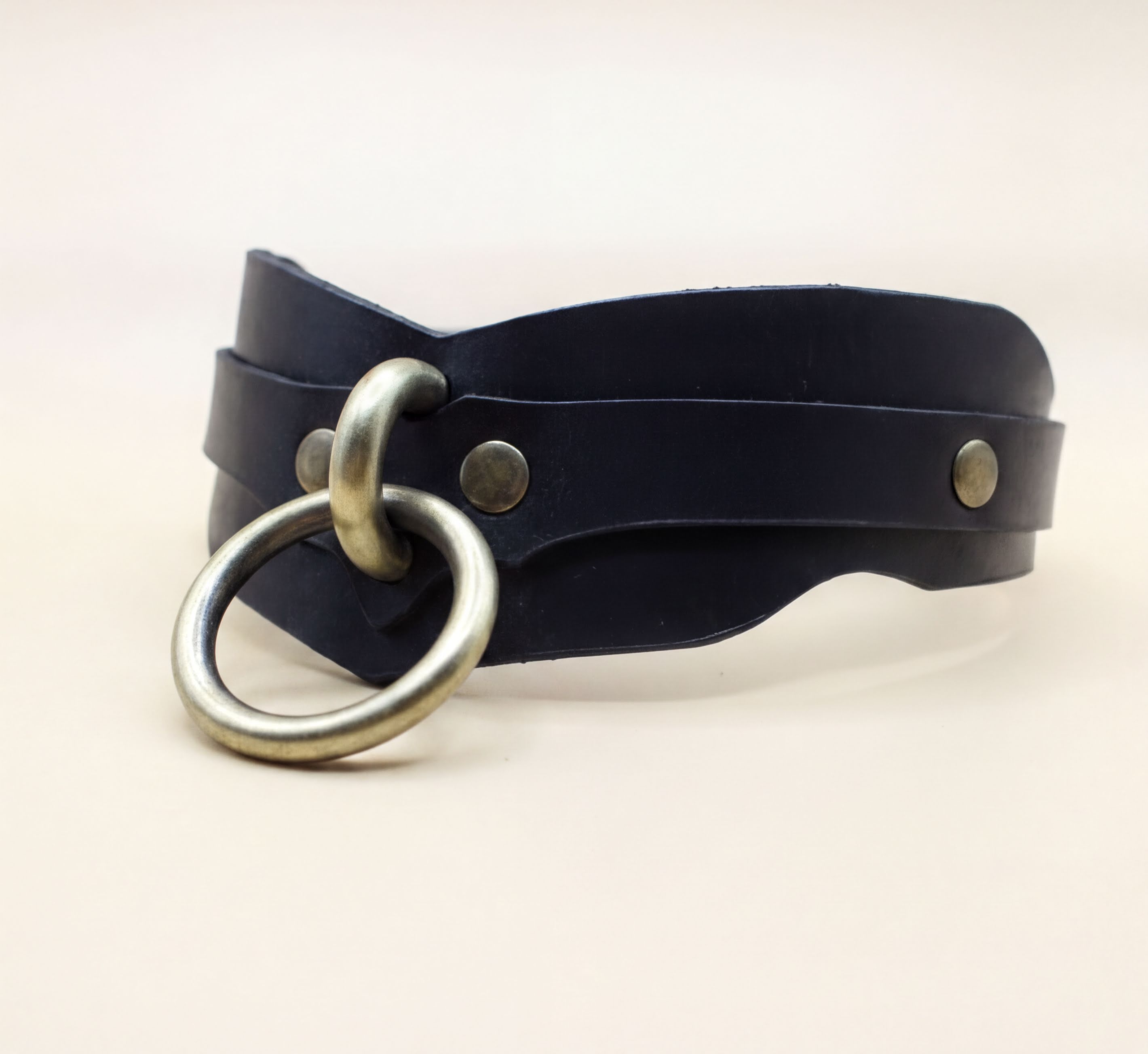 A black leather choker necklace with a metal ring and two metal buttons.