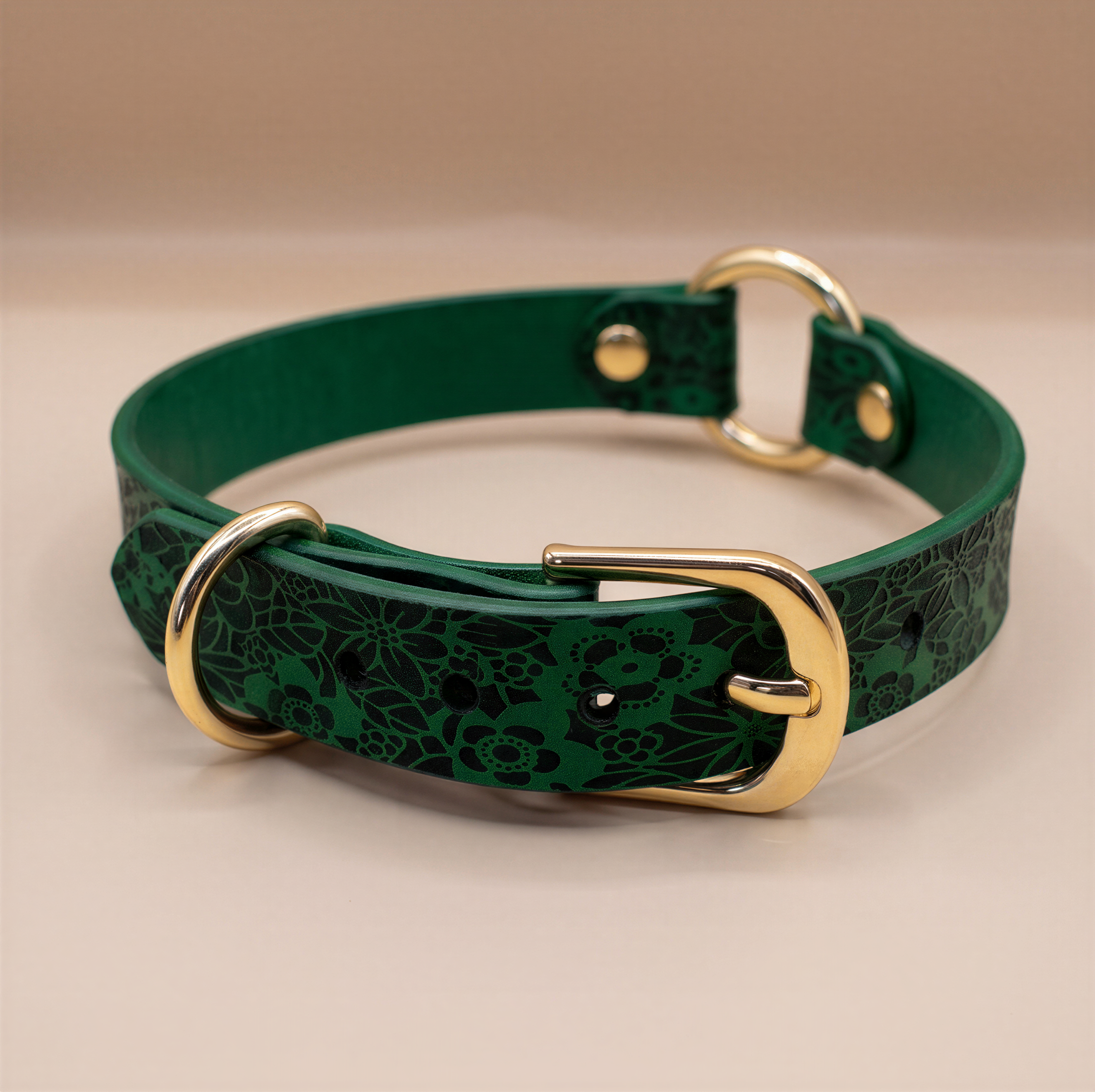 A green leather collar with a floral pattern and two gold buckles.