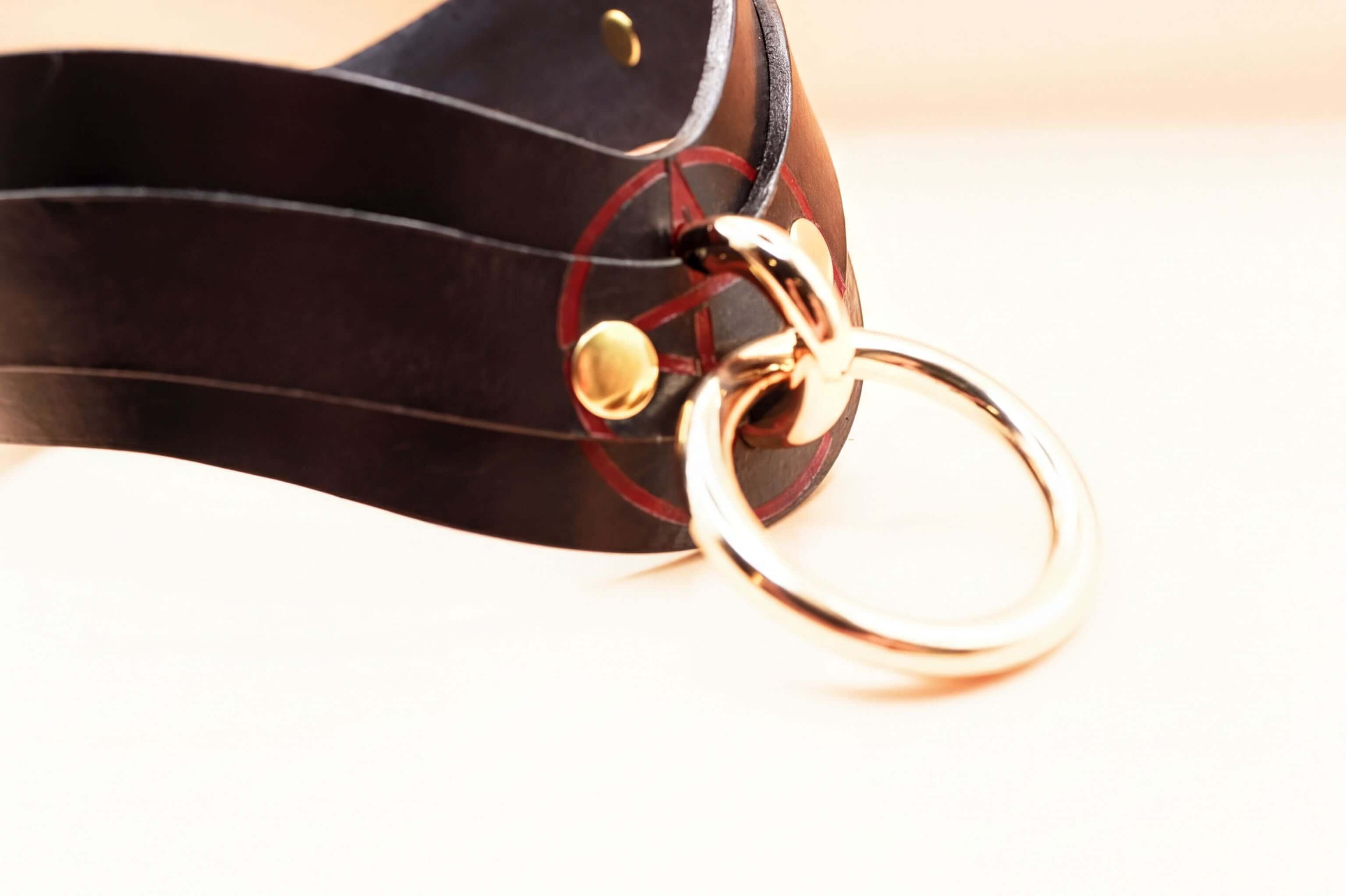Close-up of a black leather BDSM collar with gold hardware, perfect for submissive jewelry and discreet day collar wear.