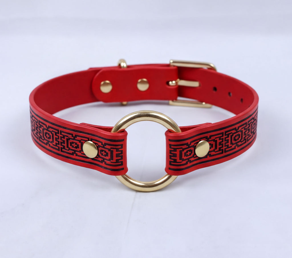 A red and black patterned choker necklaces with a gold ring and buckle.