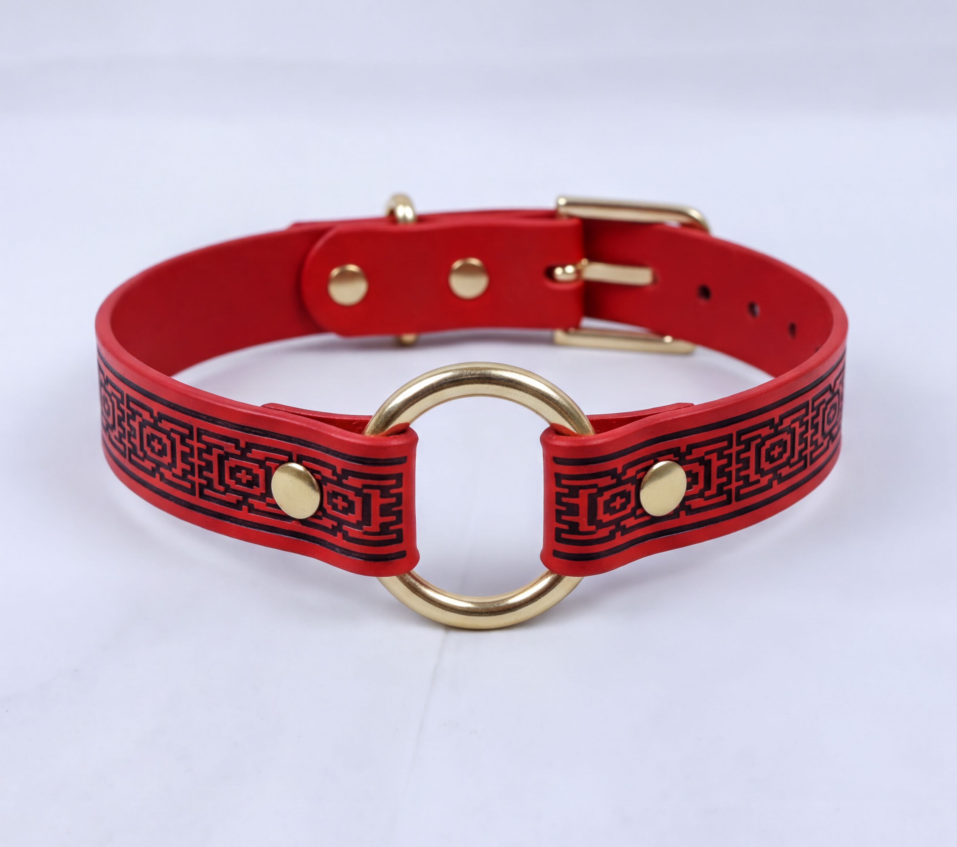 A red and black patterned choker necklaces with a gold ring and buckle.