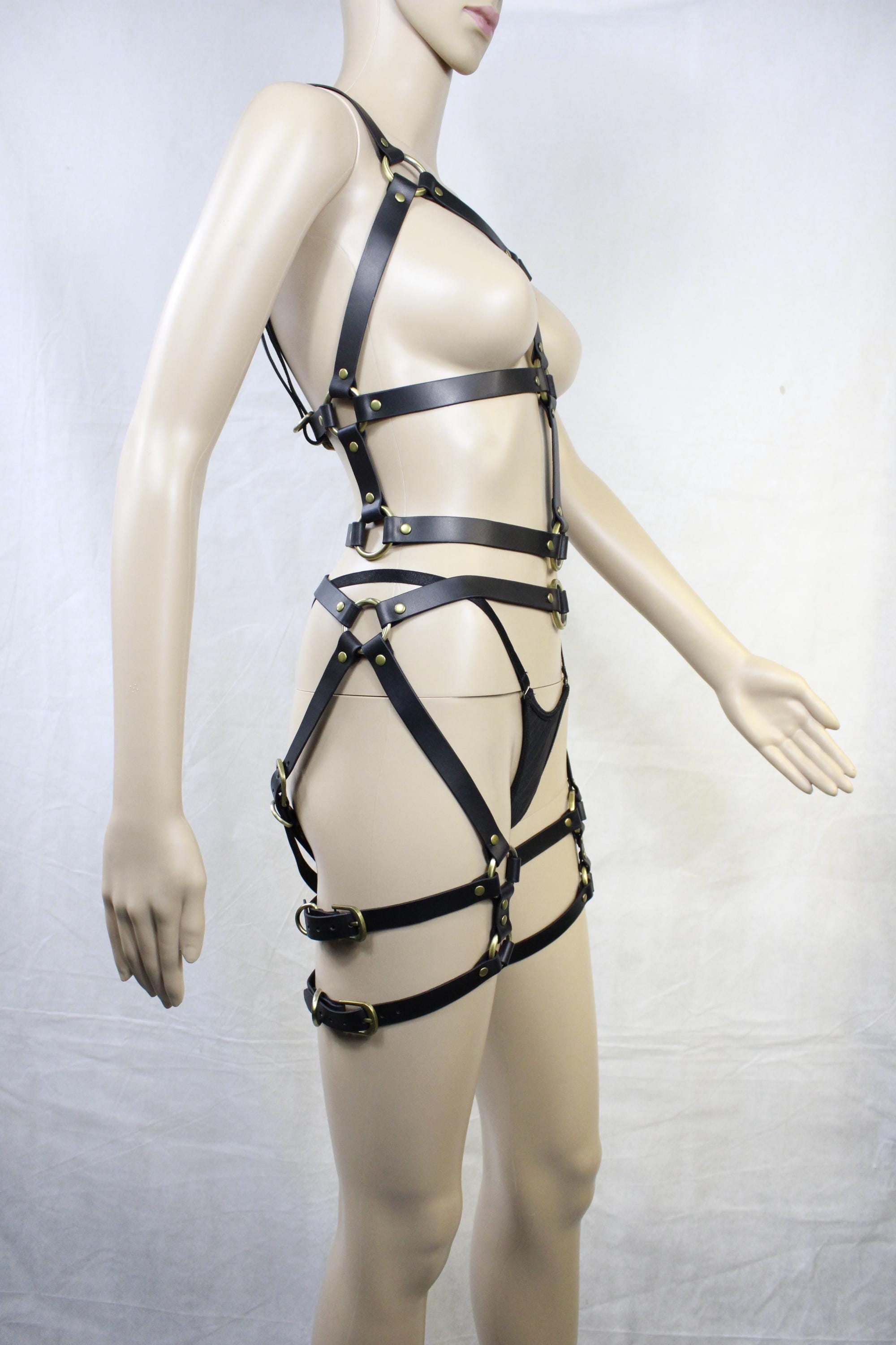A mannequin wearing a leather strap ensemble, including straps and buckles, is shown in the image.