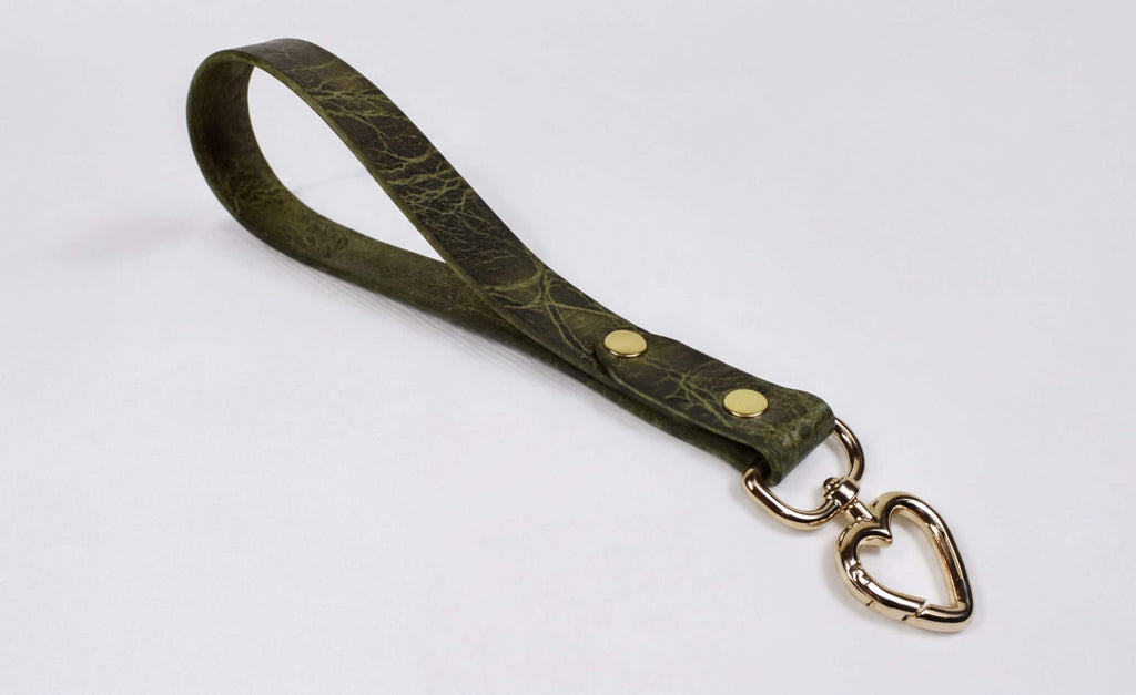 A green leather strap with a heart-shaped metal clasp attached to it.