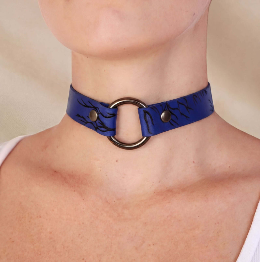A close-up of a person wearing a blue choker necklace with a black floral pattern.