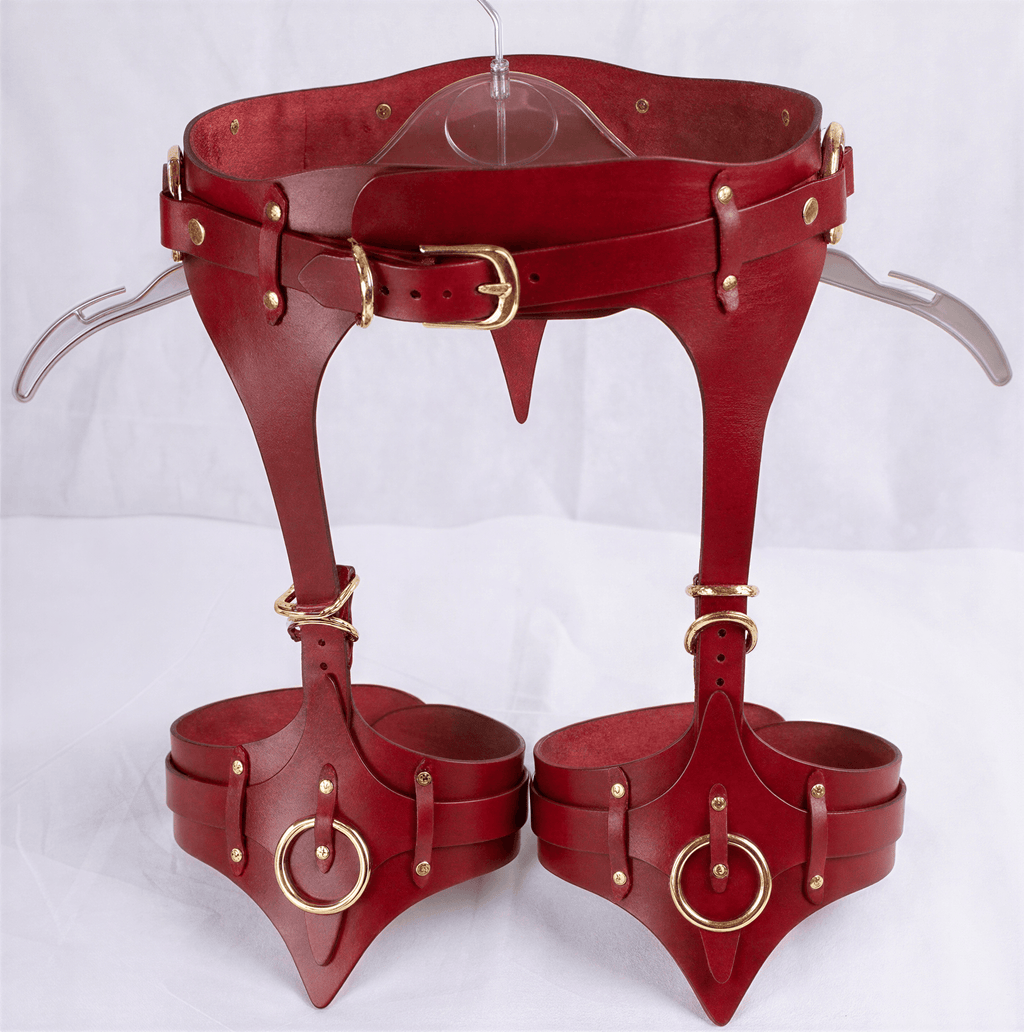 A pair of red leather corsets with metal studs and buckles, displayed on a hanger.
